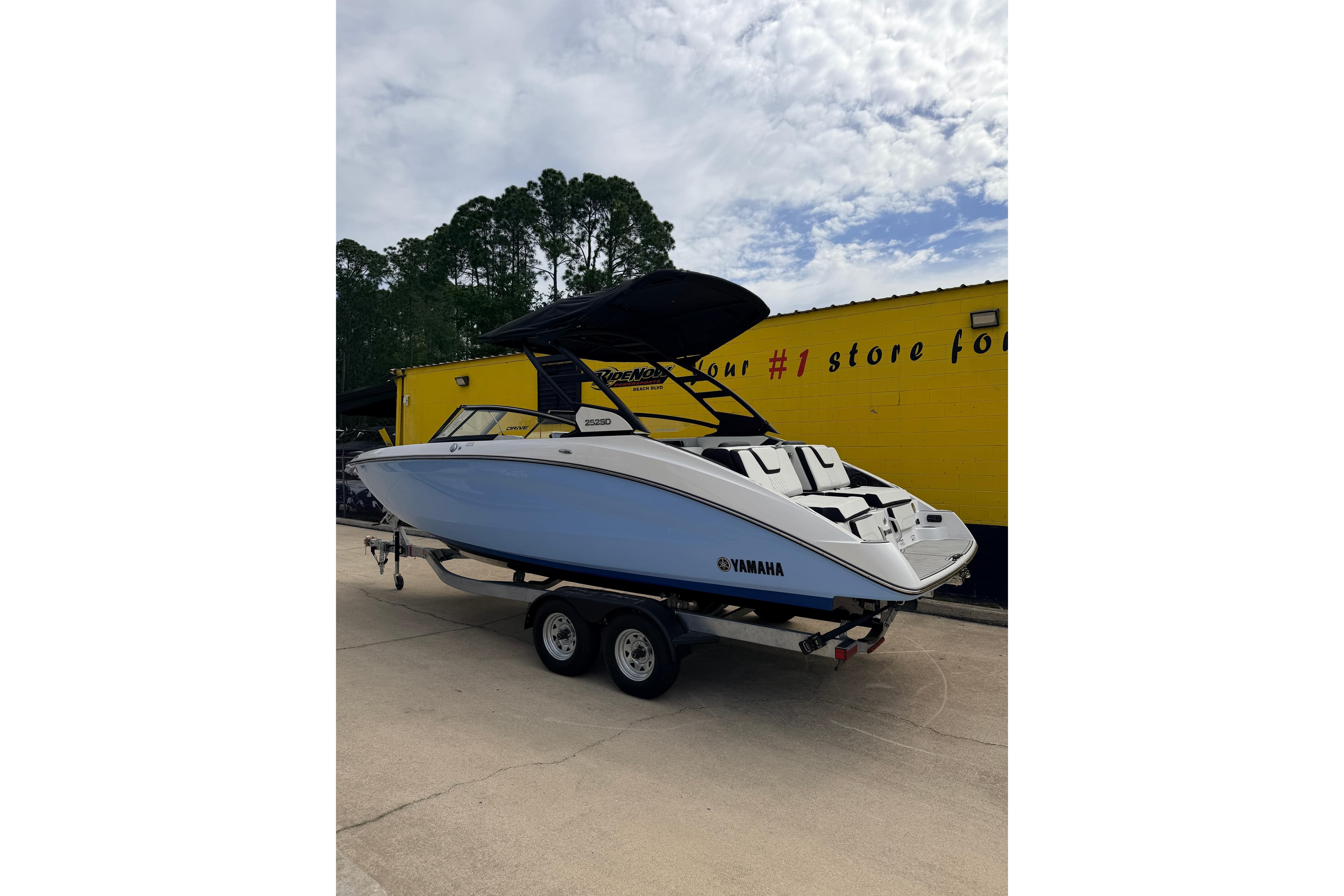 2026 Yamaha Boats 252SD on trailer, parked outdoors near a yellow building.