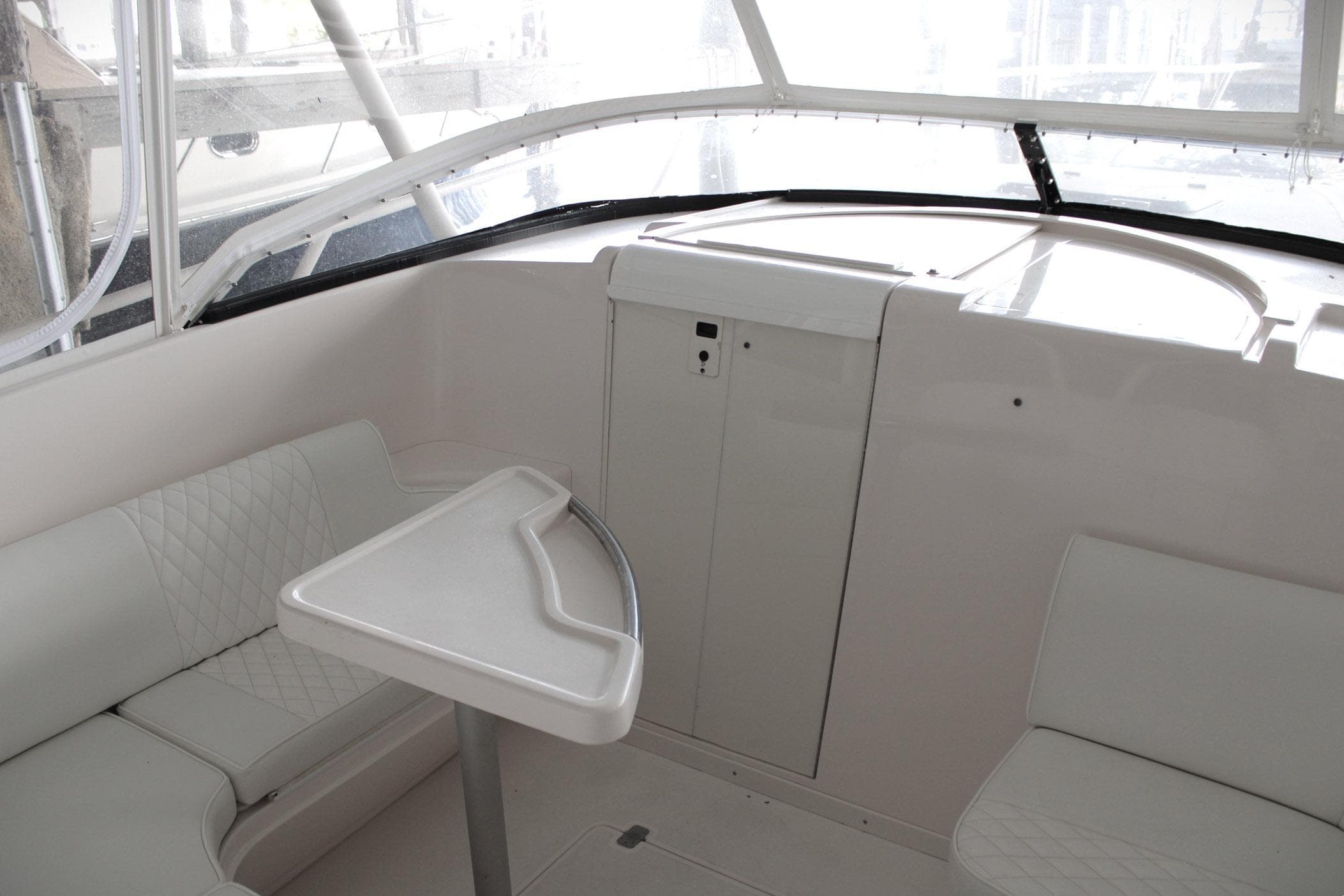 Interior of a 2001 Intrepid 366 boat featuring white seating and a compact table.