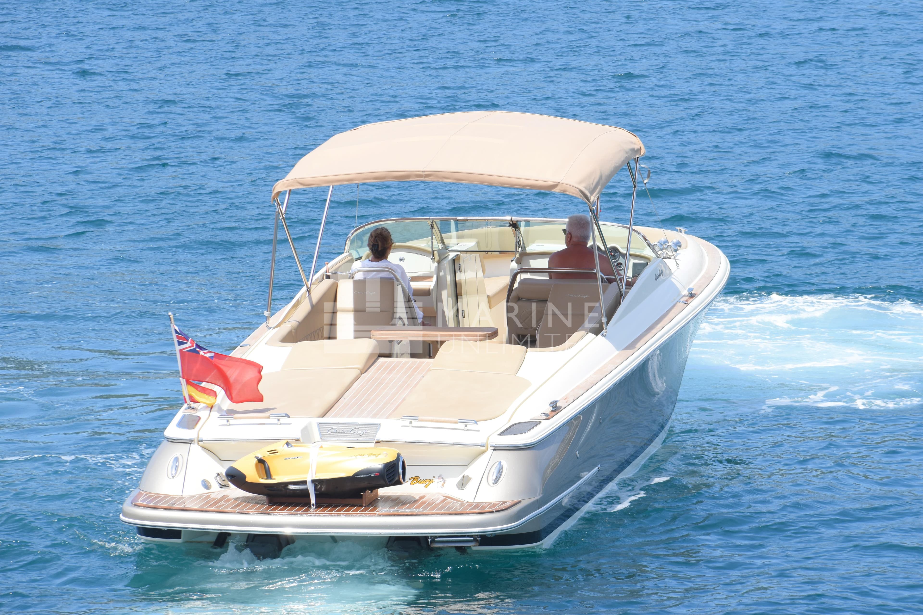 2015 Chris-Craft Launch 32 boat cruising on clear blue water with passengers.