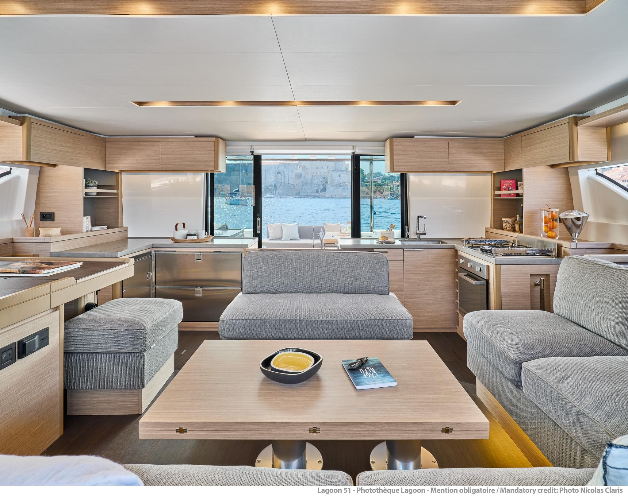 Luxurious interior of 2025 Lagoon 51 ICONIC yacht with modern kitchen and seating area.