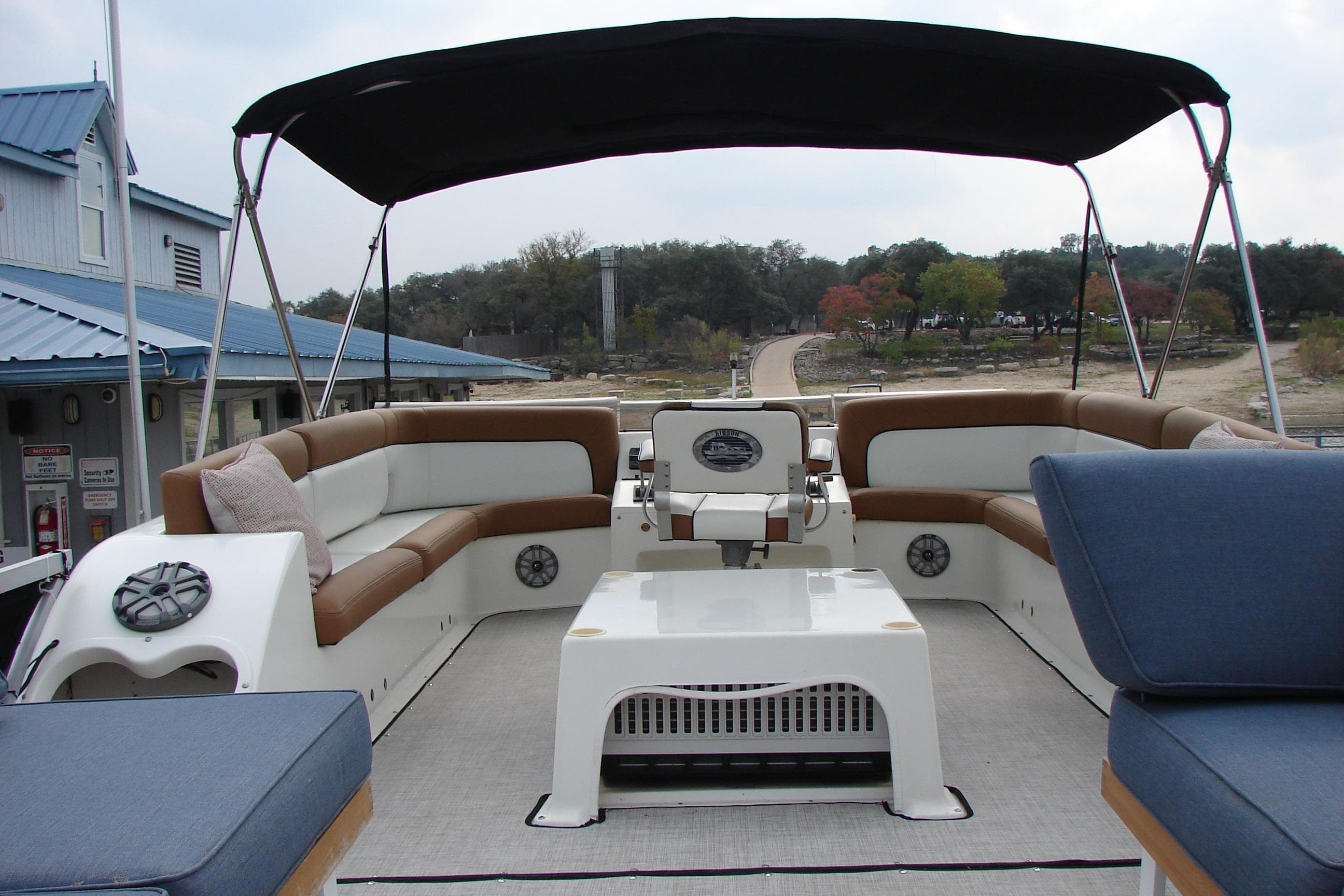 1997 Gibson 47 Sport Houseboat with spacious seating and canopy, docked near a scenic shoreline.