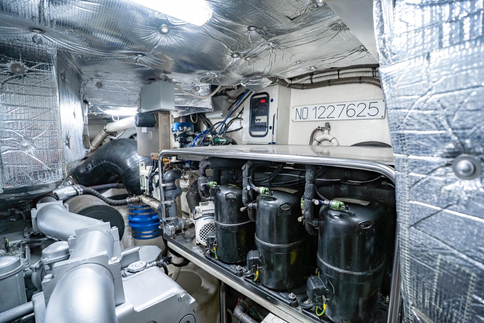Engine room of a 2010 Pershing 80 yacht, showcasing machinery and insulation.
