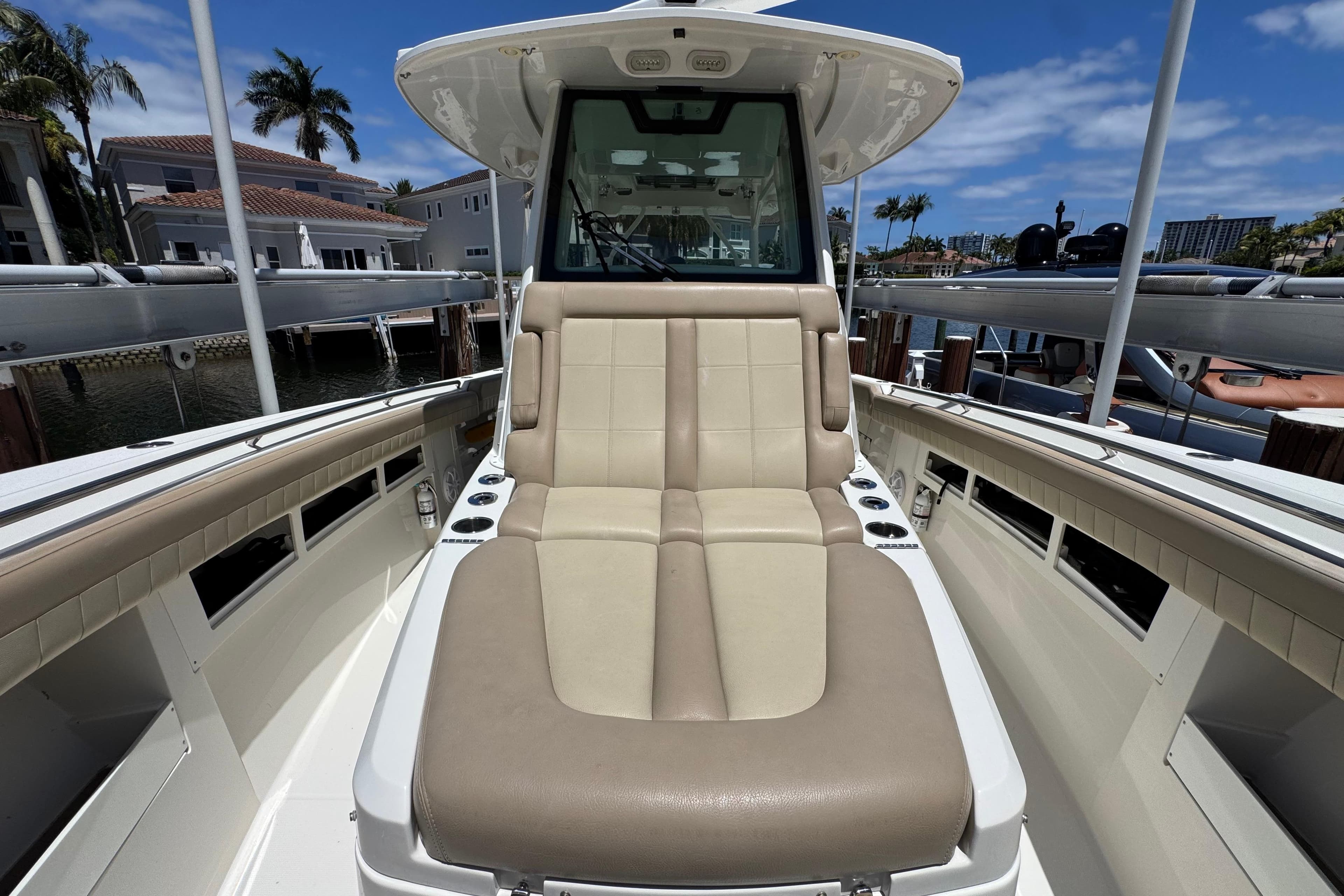 2019 Sailfish 360 CC boat interior with beige seating, docked near waterfront homes.
