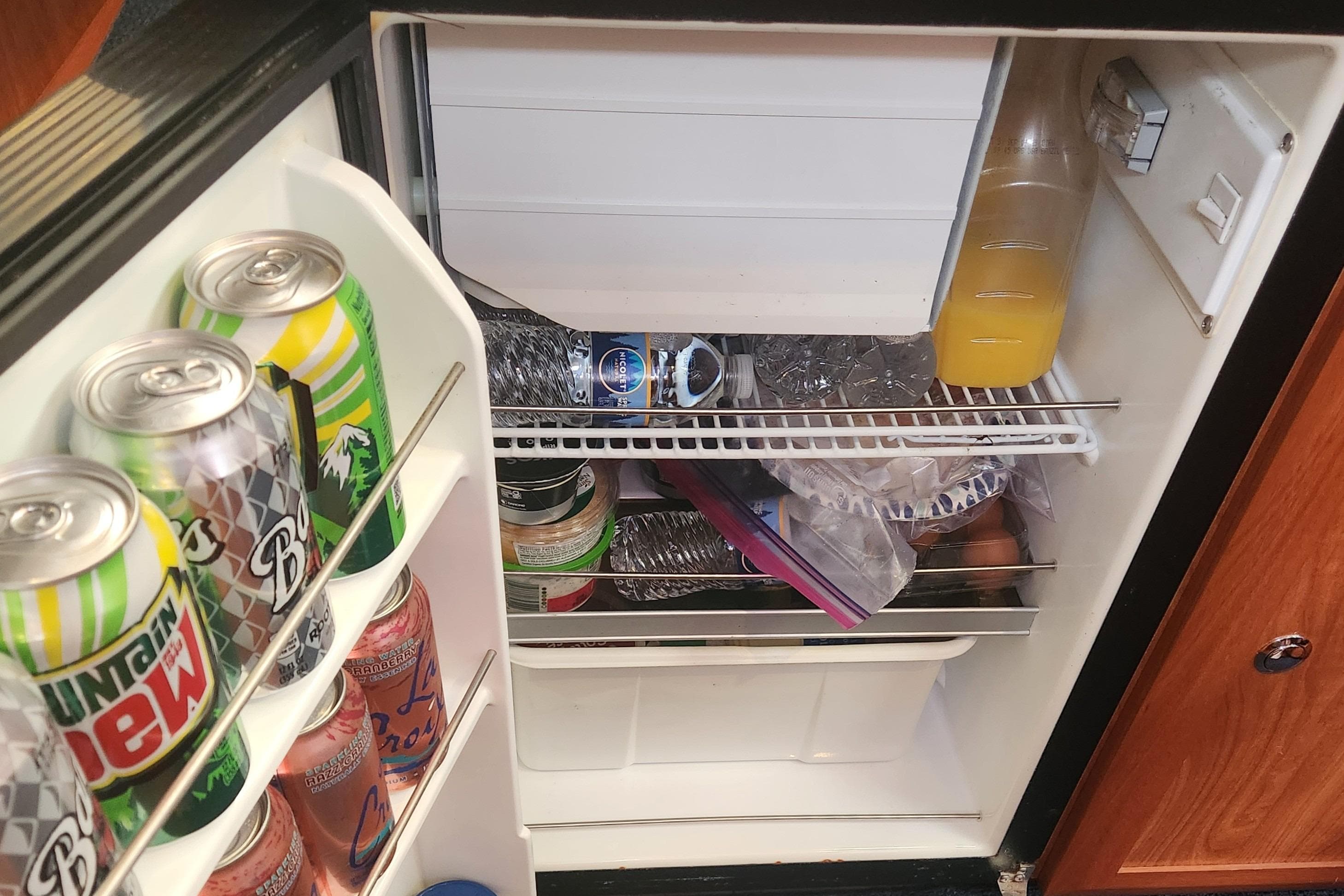 Mini fridge stocked with drinks and food, inside a 2011 Hunter 39 boat.