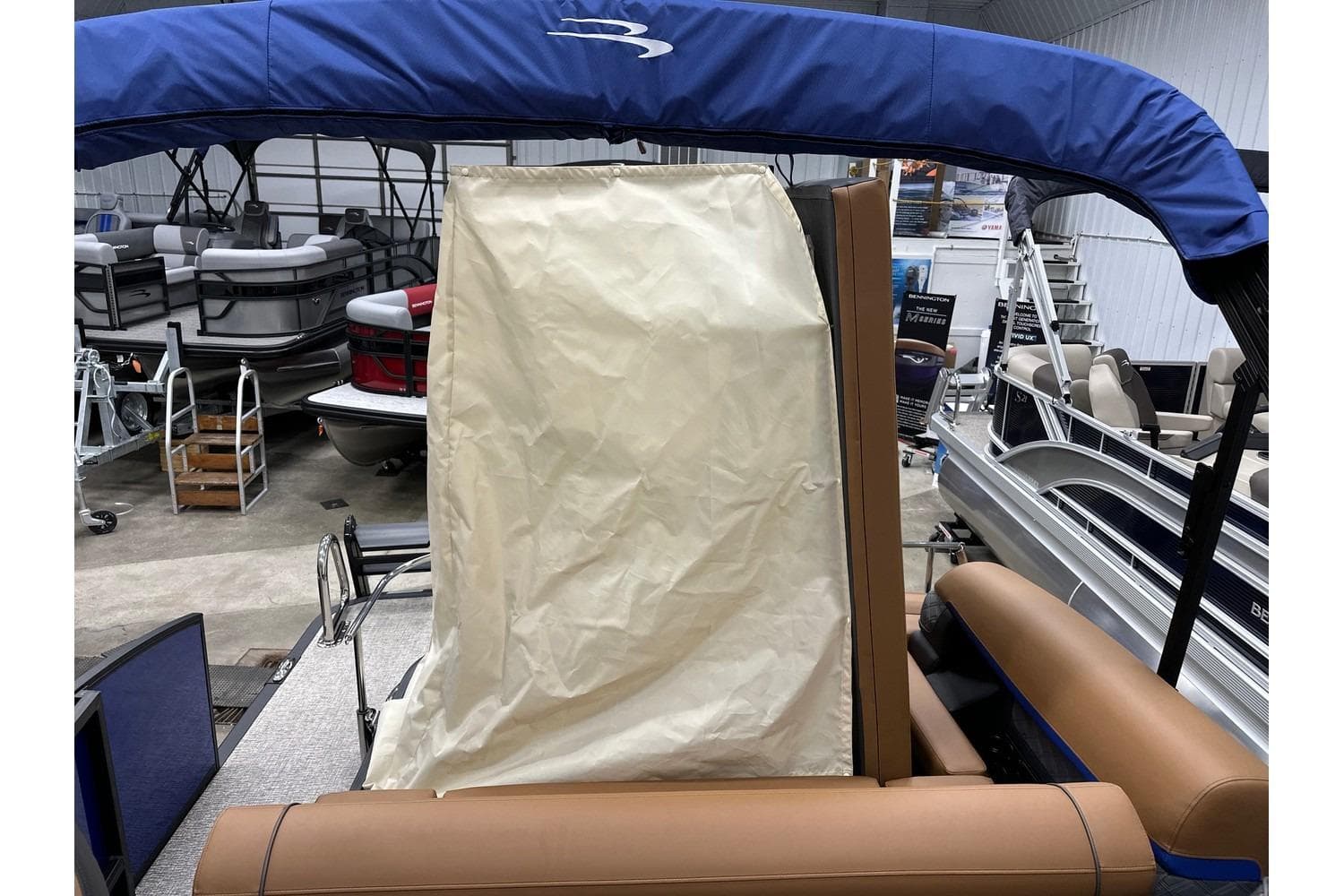 2026 Bennington 22 SSB Swingback pontoon boat with blue canopy in showroom.