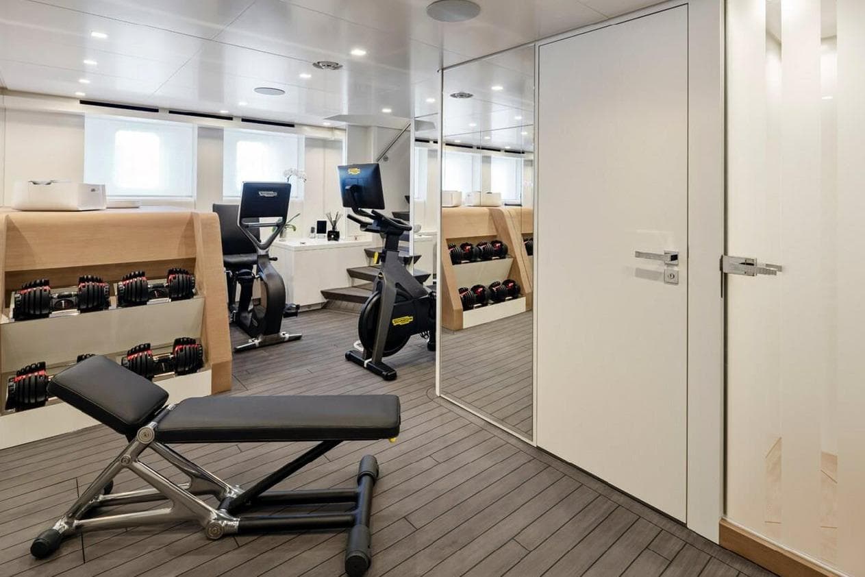 Modern gym on 2021 Heesen yacht with exercise equipment and weights.