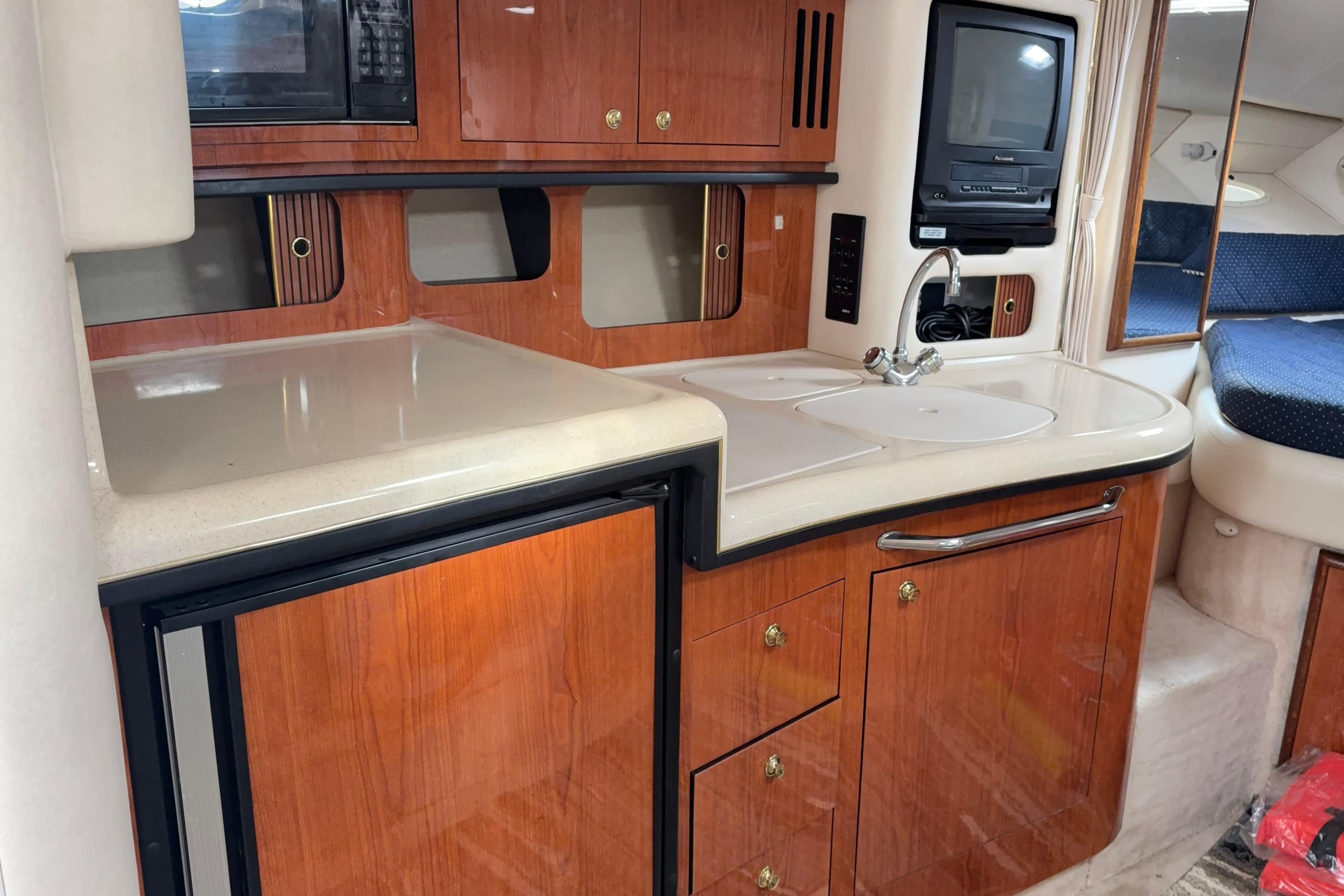 2000 Sea Ray 340 Sundancer interior kitchen with wood cabinetry and compact appliances.