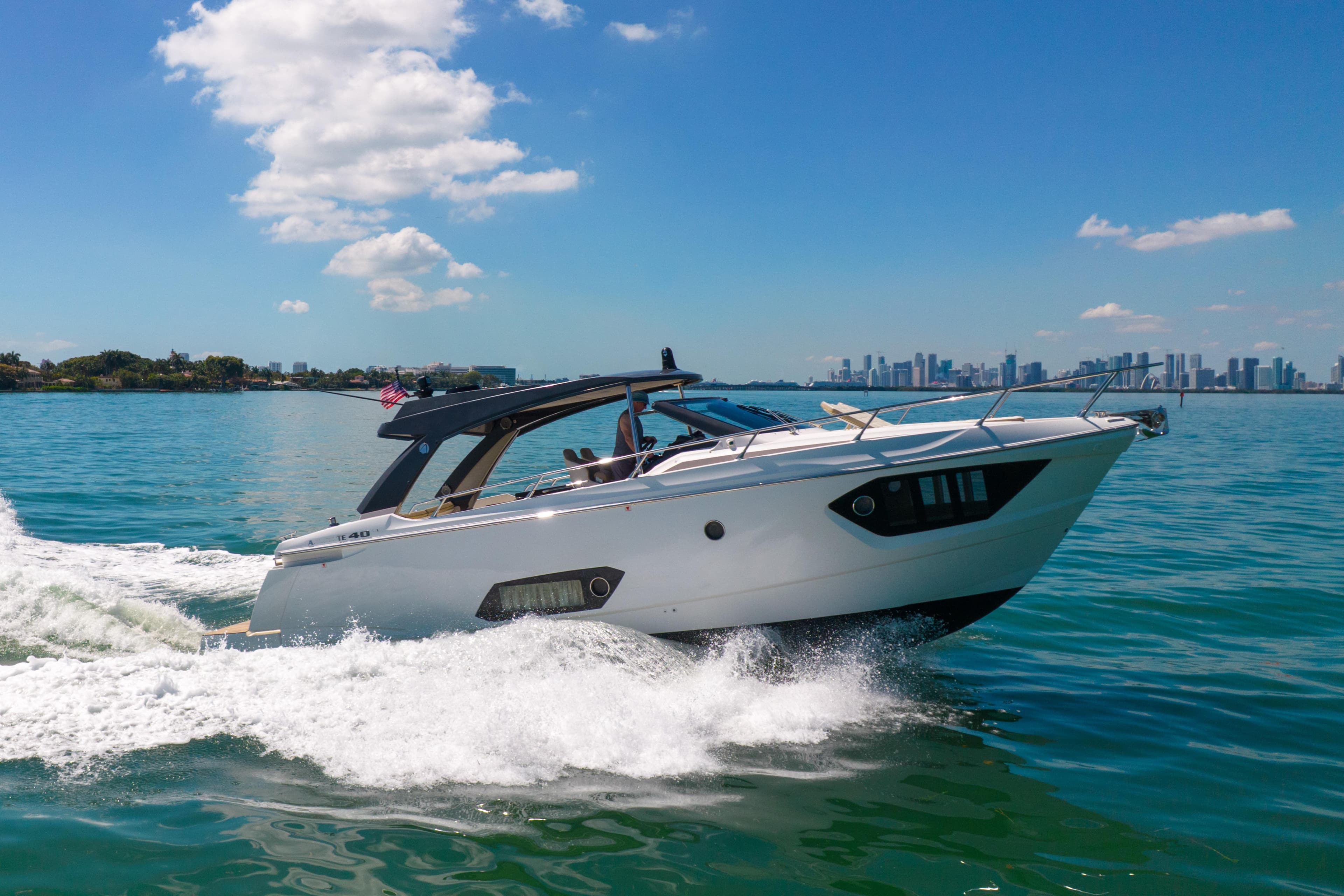 2017 Absolute 40 STL yacht cruising on blue water with city skyline backdrop.
