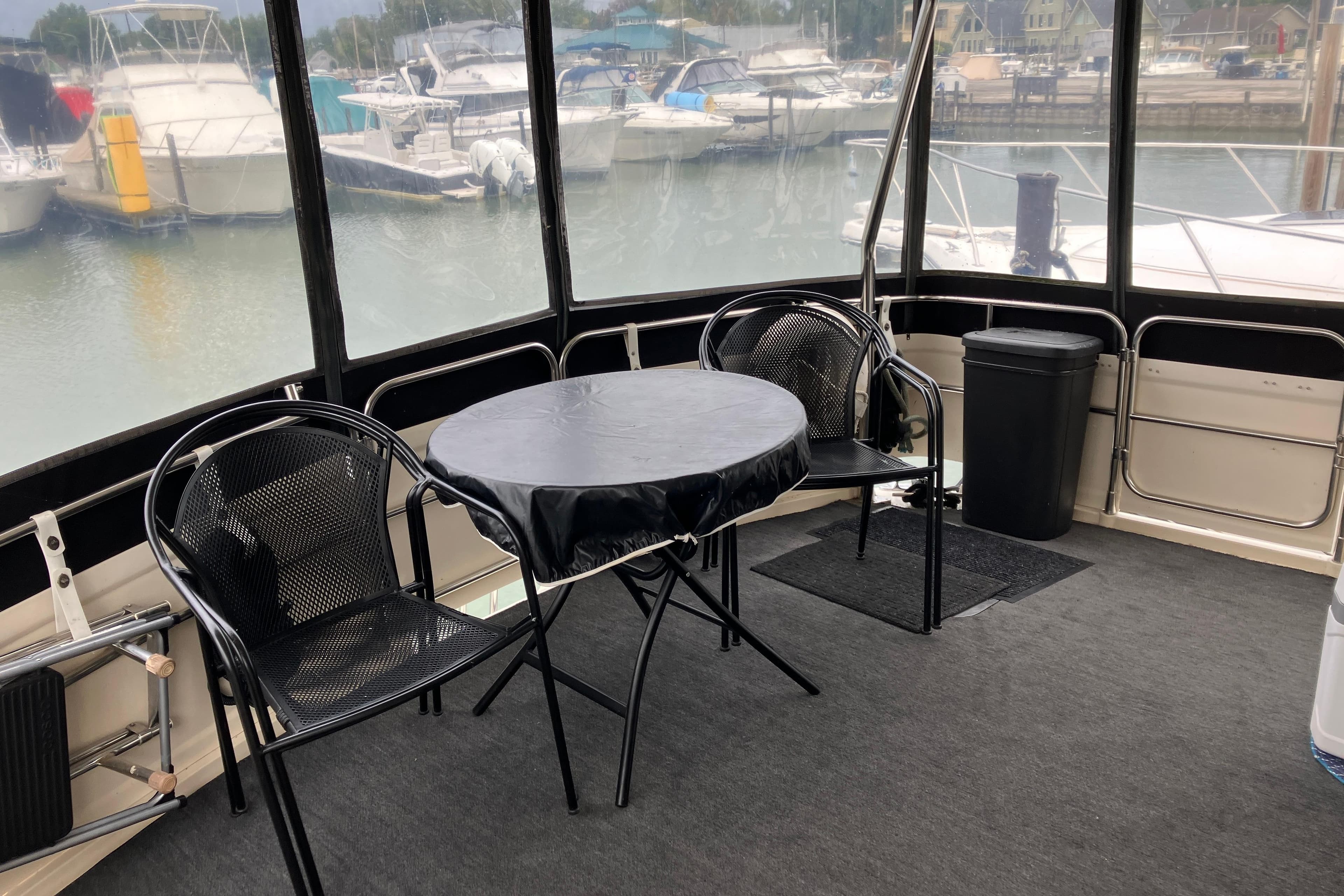 1987 President 37 Sundeck yacht interior with table, chairs, and marina view.