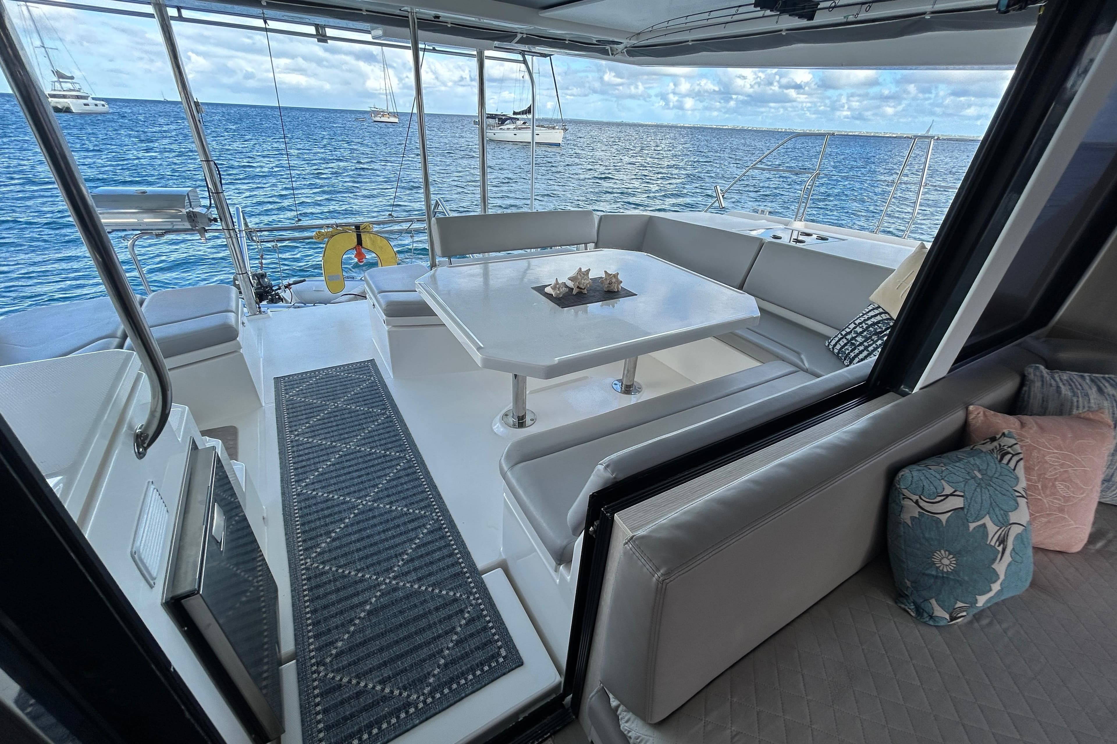 Leopard 45 catamaran's outdoor seating area with ocean view, featuring a table and cushions.