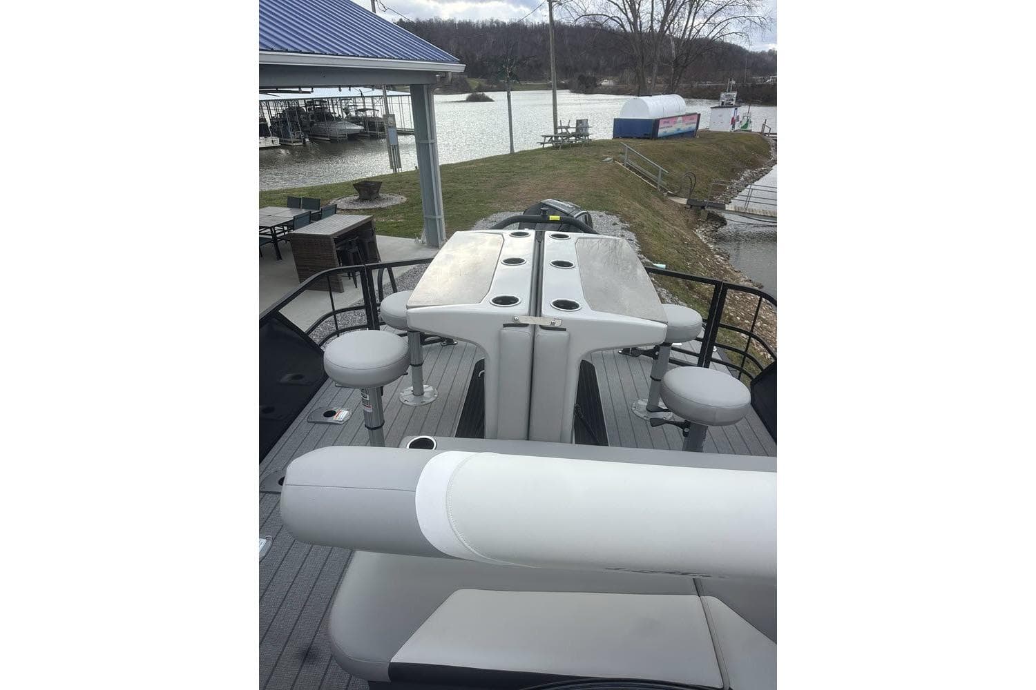 2026 SunChaser Eclipse 25 SBX DH BAR pontoon boat with bar seating, docked by a lakeside.