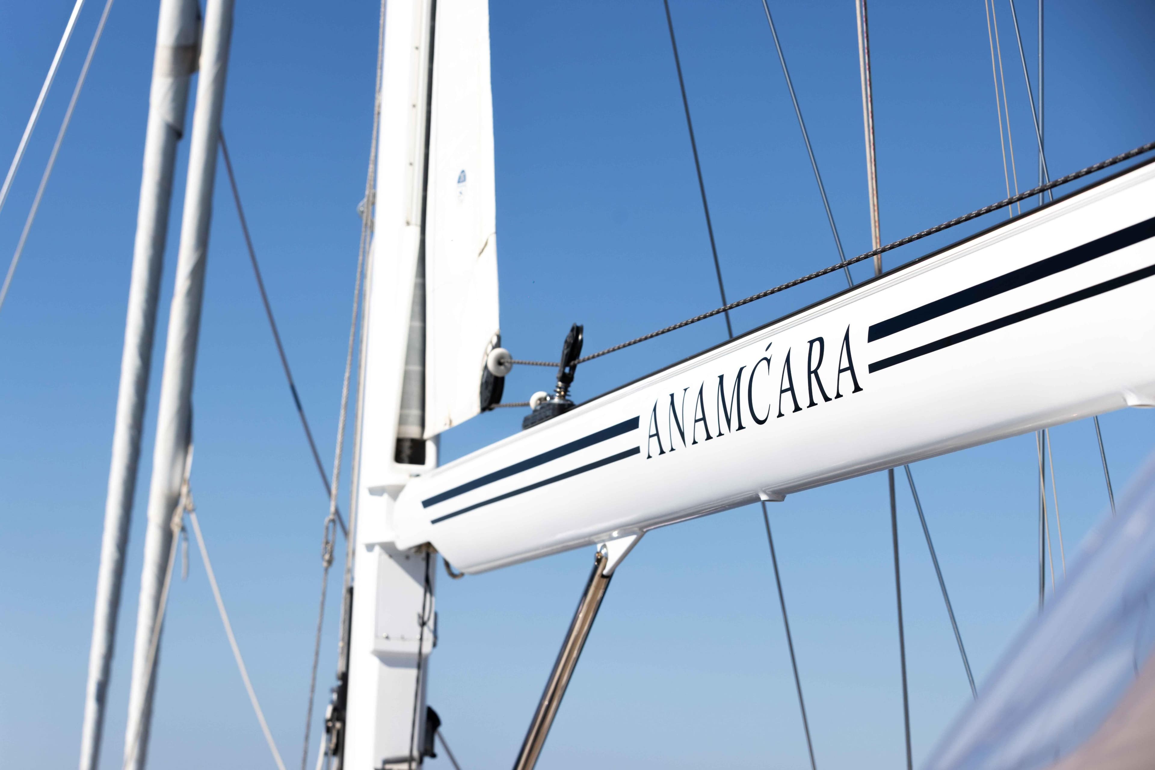 Sailboat mast with "Anamcára" text, Jongert 31, 2001 model, against clear blue sky.