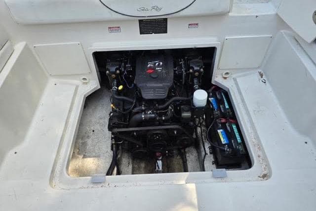 Engine compartment of a 2004 Sea Ray 215 Weekender boat, showcasing the engine and battery.