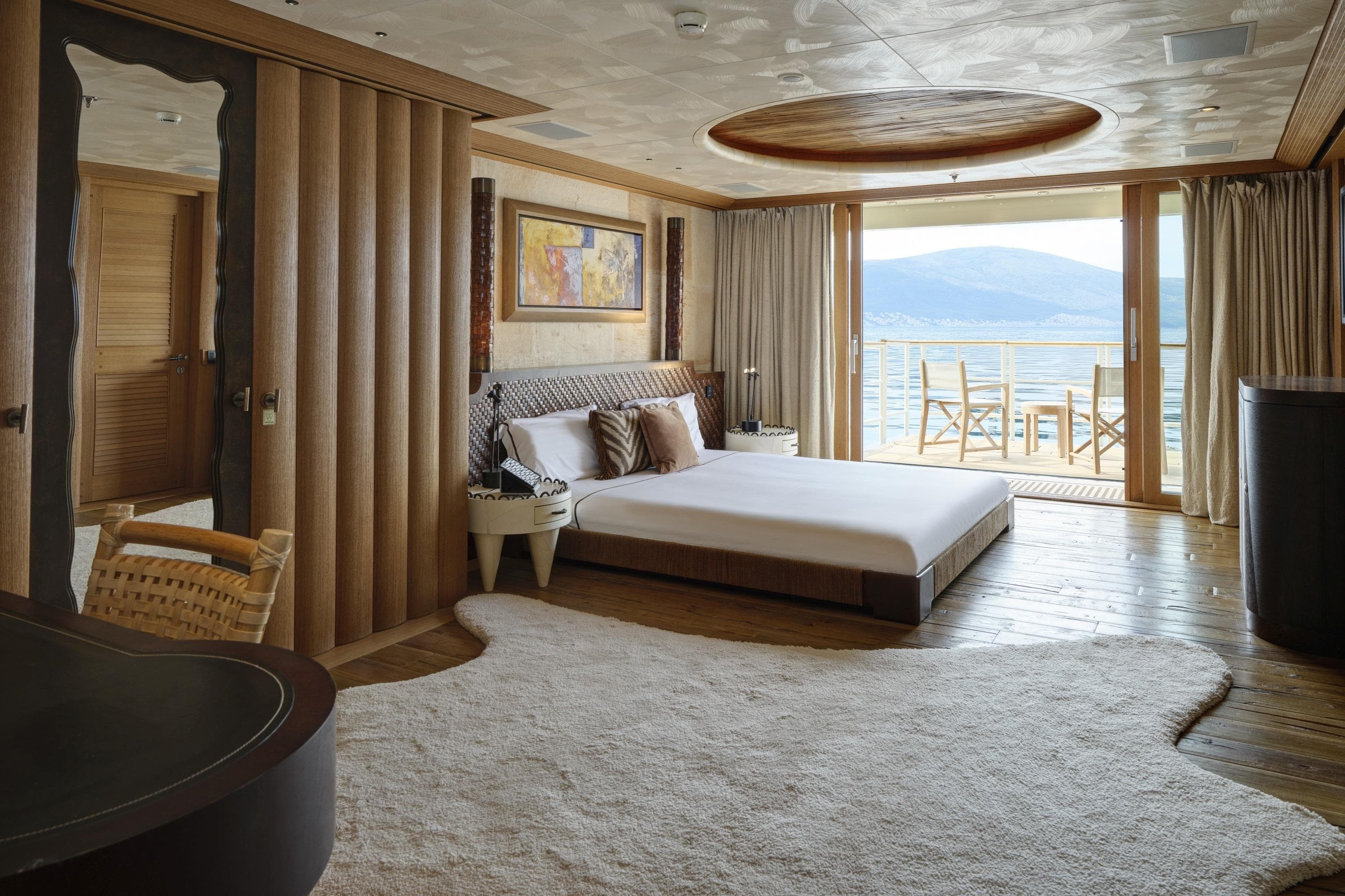 Luxurious bedroom on 2003 Lurssen custom-built yacht with ocean view and elegant decor.