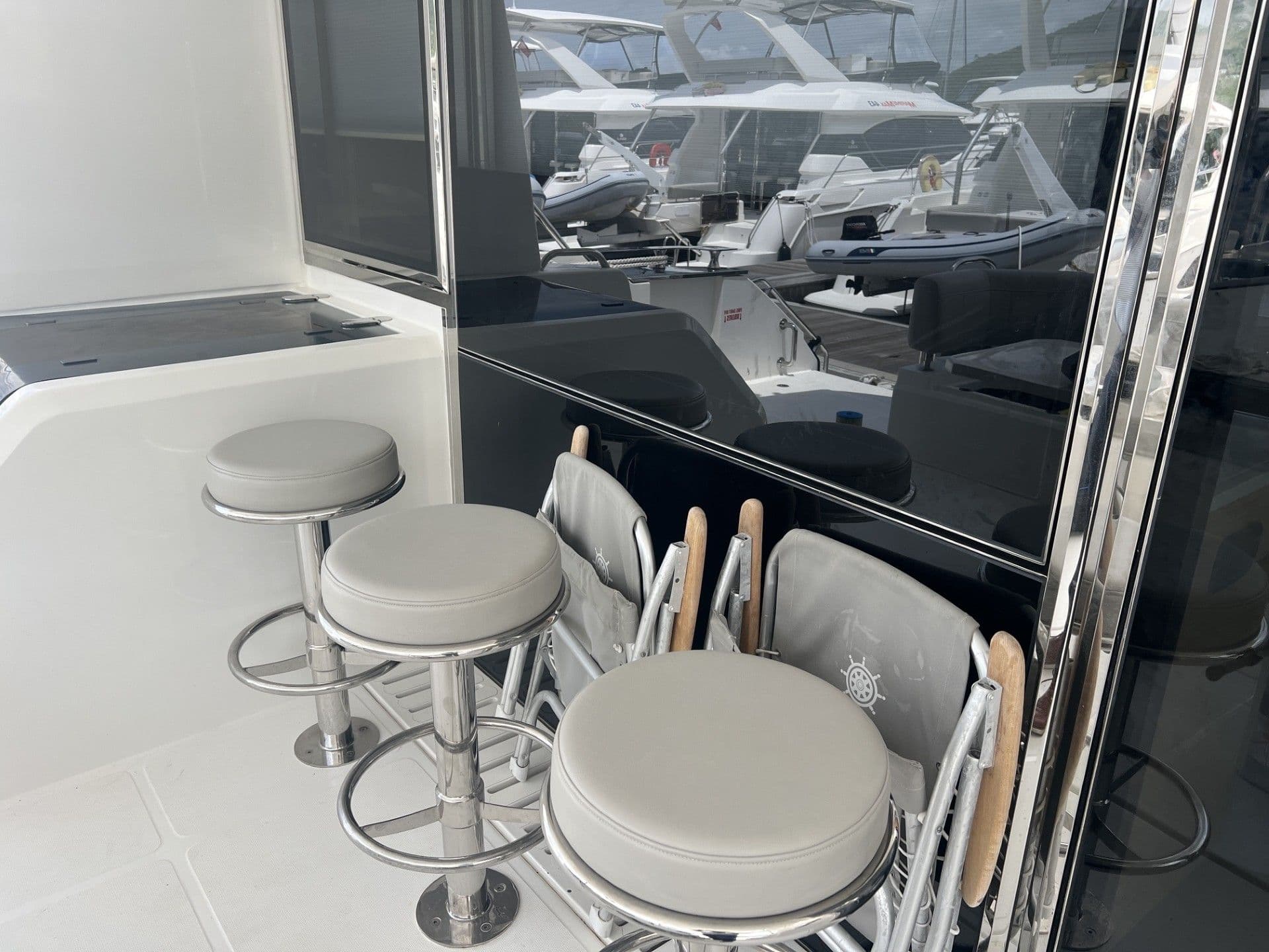 Interior of 2023 Aquila 54 Yacht with bar stools and folding chairs.