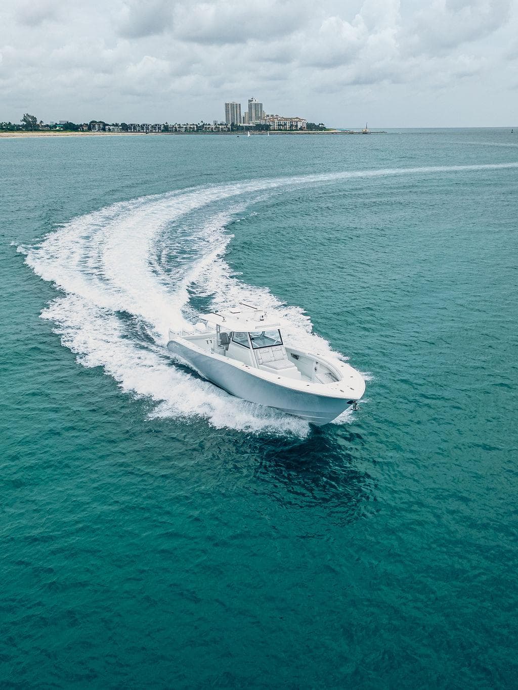 2019 Yellowfin 42 boat cruising on turquoise ocean near coastline.
