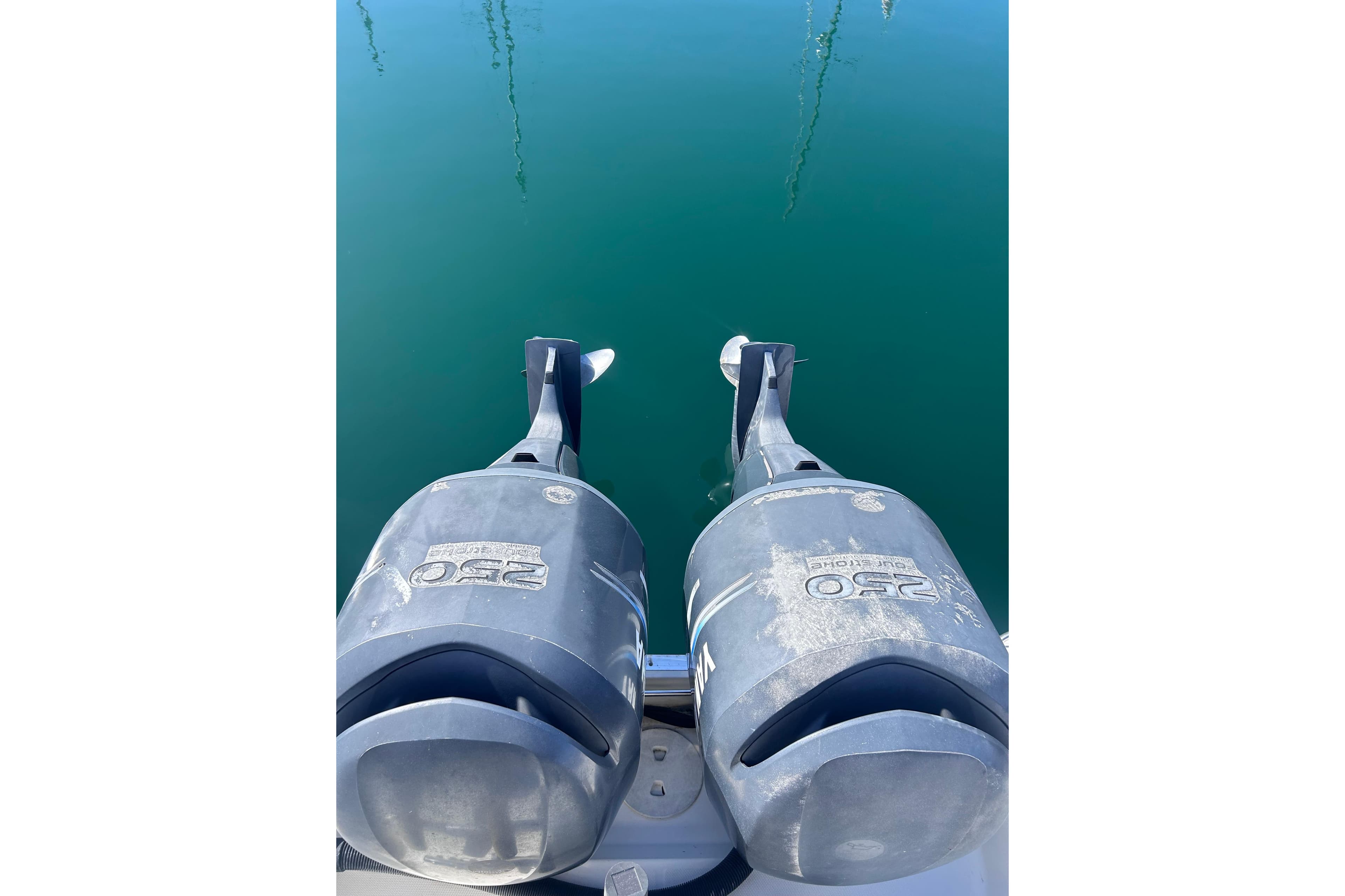Twin outboard motors on a 2006 Wellcraft 290 Coastal boat, reflecting on calm water.