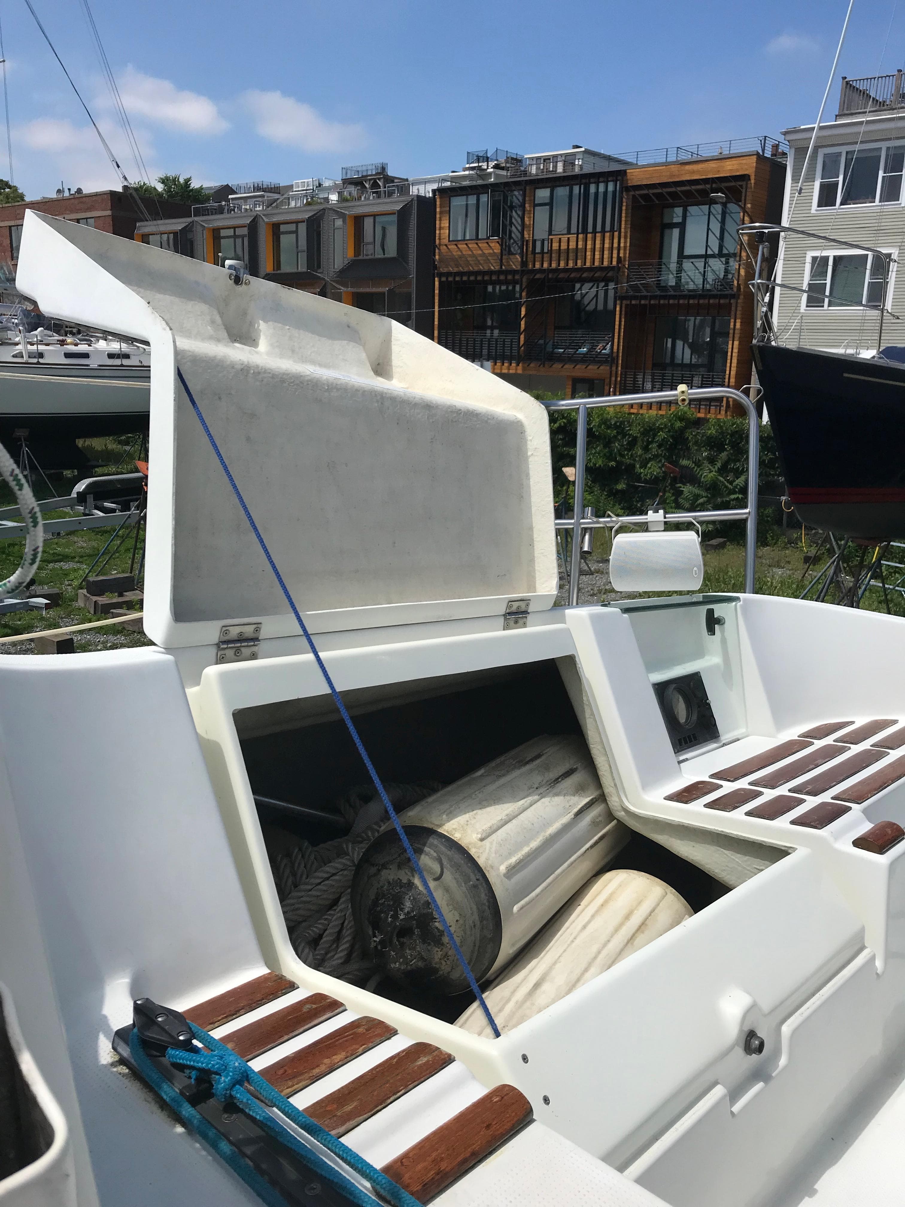 Beneteau First 310 sailboat cockpit with open storage, 1993 model, docked near modern buildings.