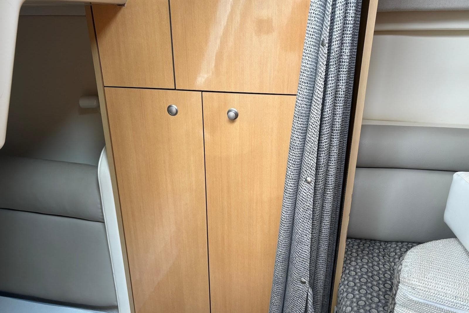Interior of 2004 Maxum 3100 SE boat with wooden cabinet and patterned curtain.