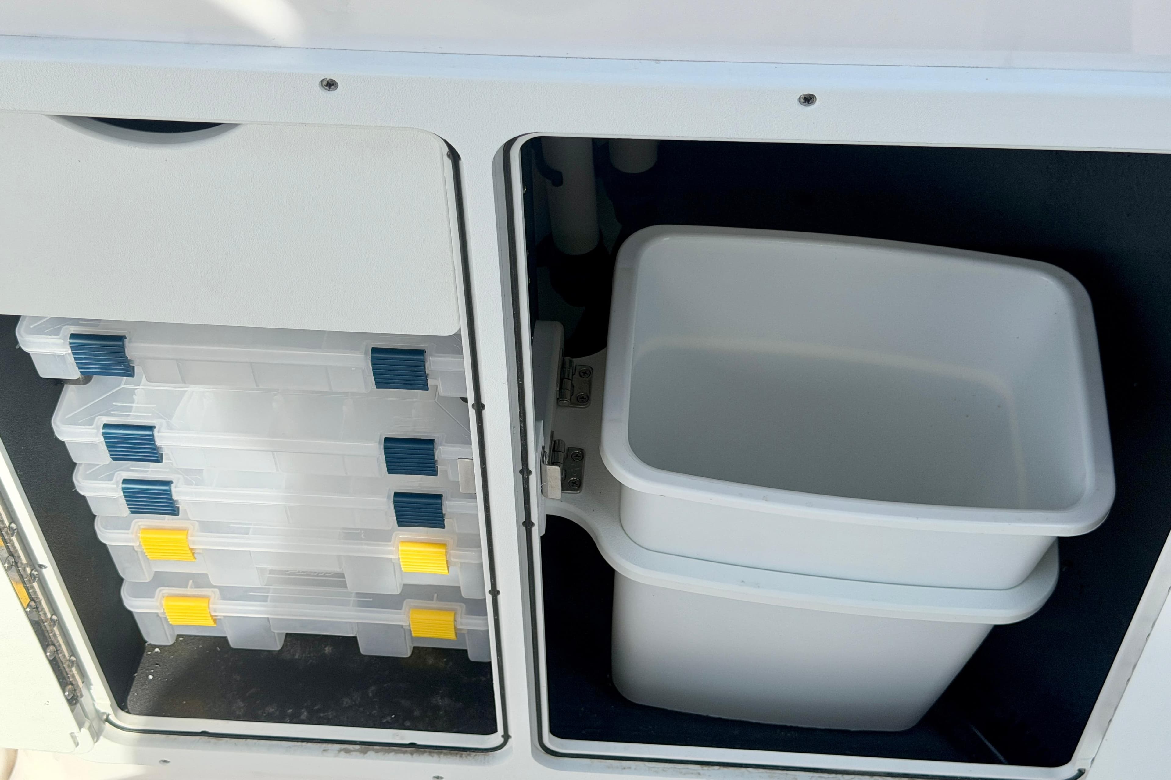 Storage compartments on a 2026 Yamaha Boats 255 FSH Sport H, featuring tackle boxes and bins.
