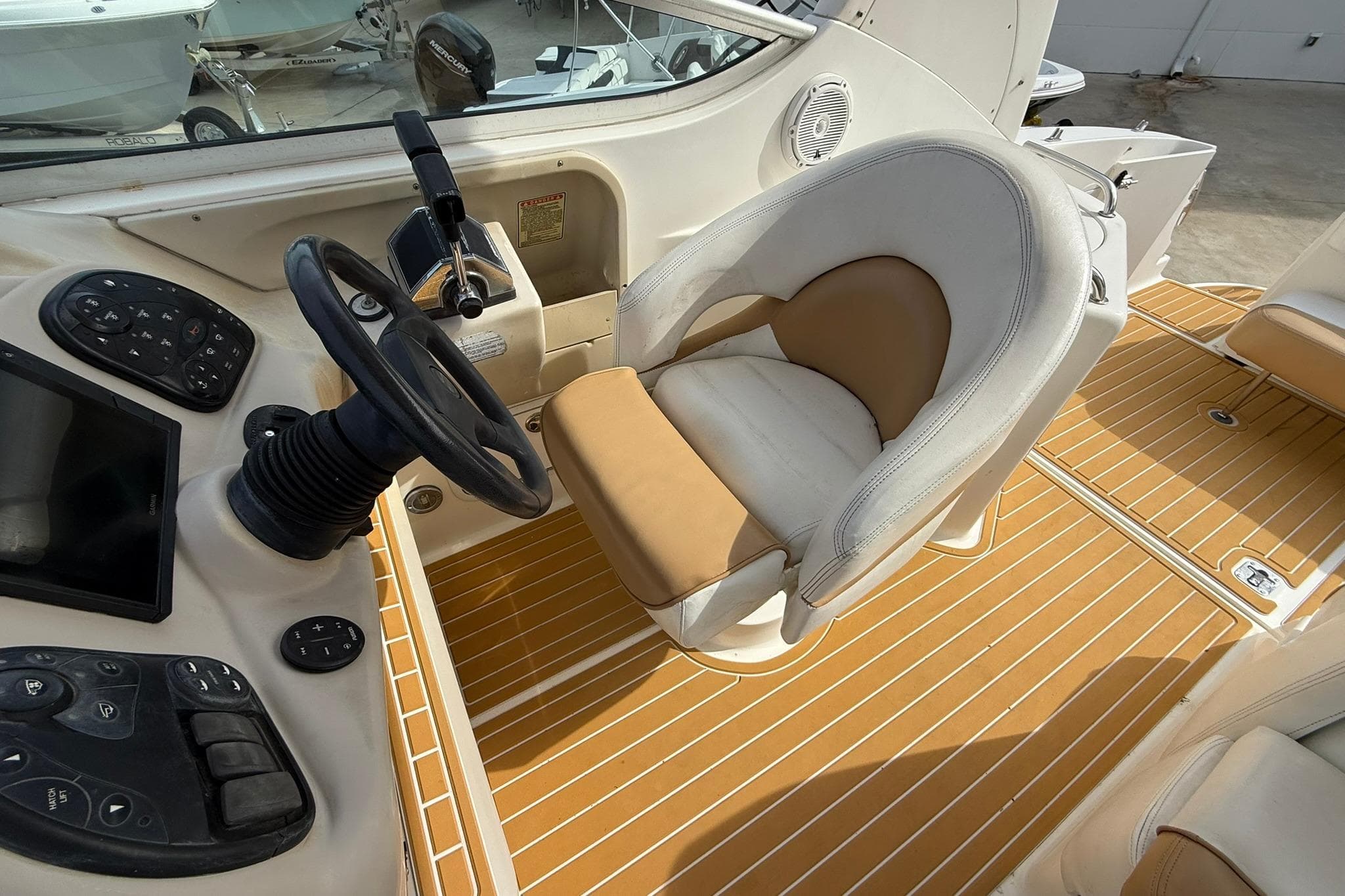 2001 Sea Ray 280 Sundancer helm with steering wheel and beige seating.