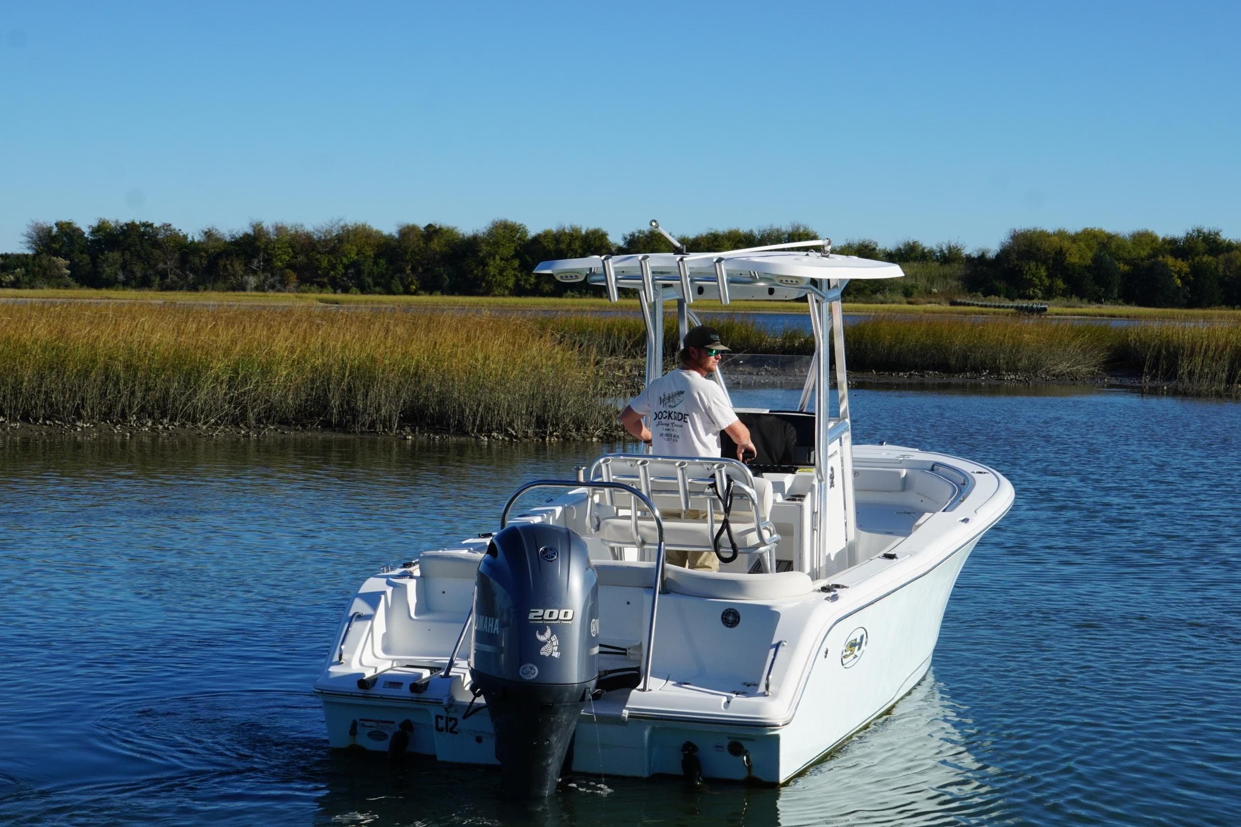 2021 Sea Hunt Ultra 229 boat navigating calm waters with scenic marshland backdrop.