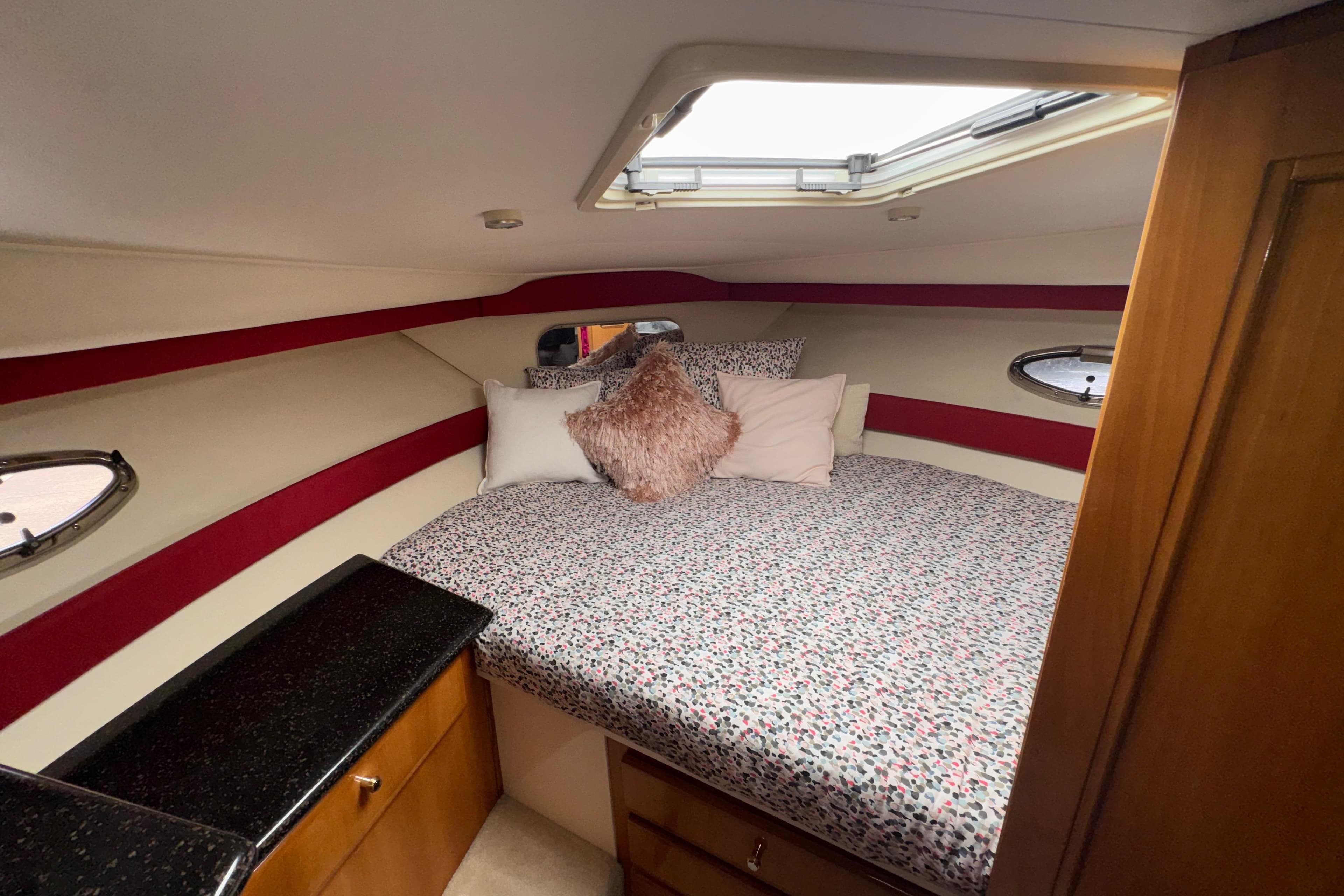 Cozy bedroom in 2001 Carver 356 Motor Yacht with patterned bedding and porthole windows.