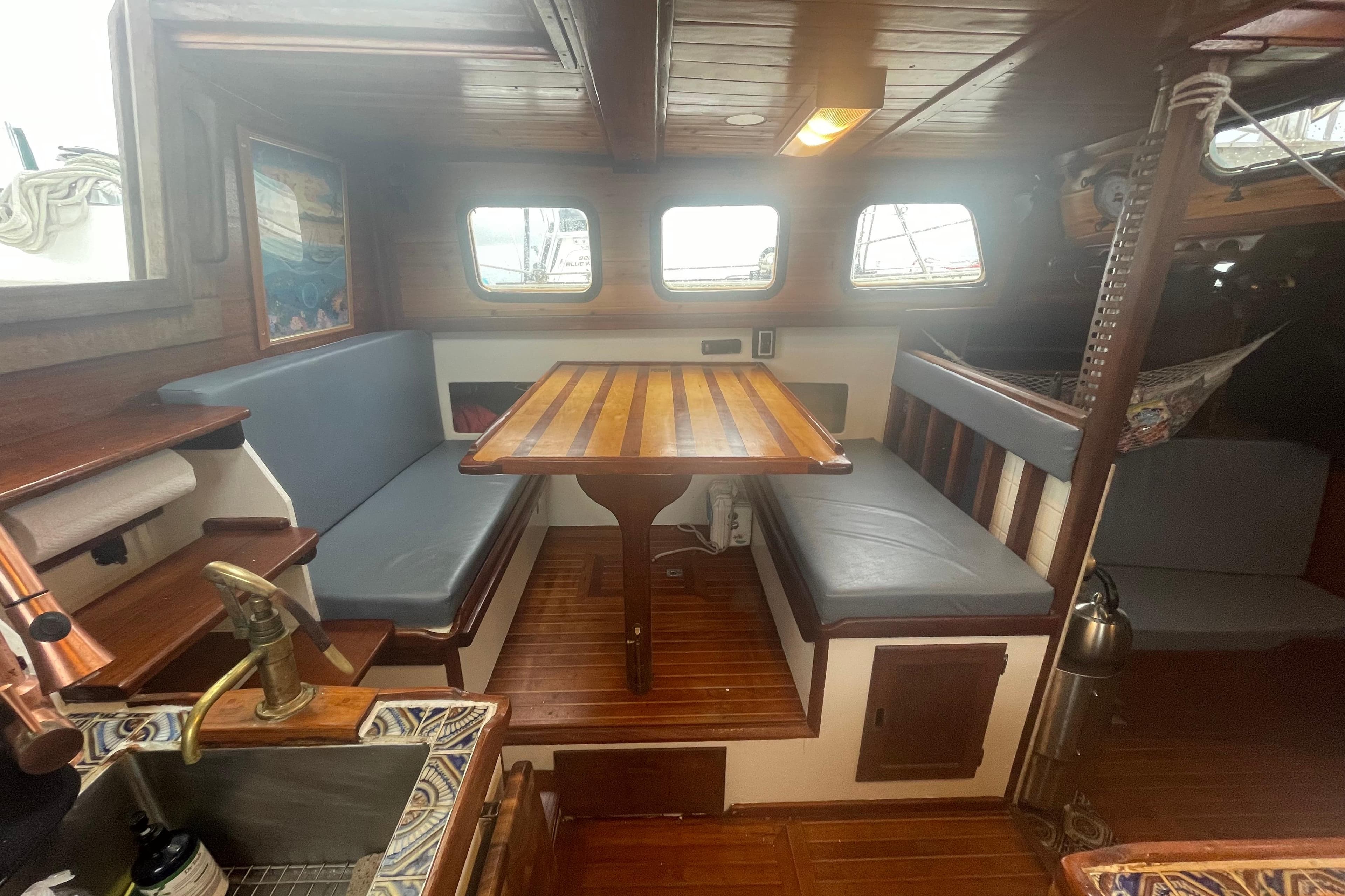 Cozy 1975 Westsail Staysail Ketch interior with wooden dining area and nautical decor.