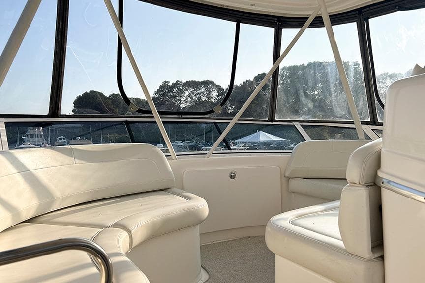Interior of 2002 Silverton 42 Convertible yacht with white seating and panoramic windows.