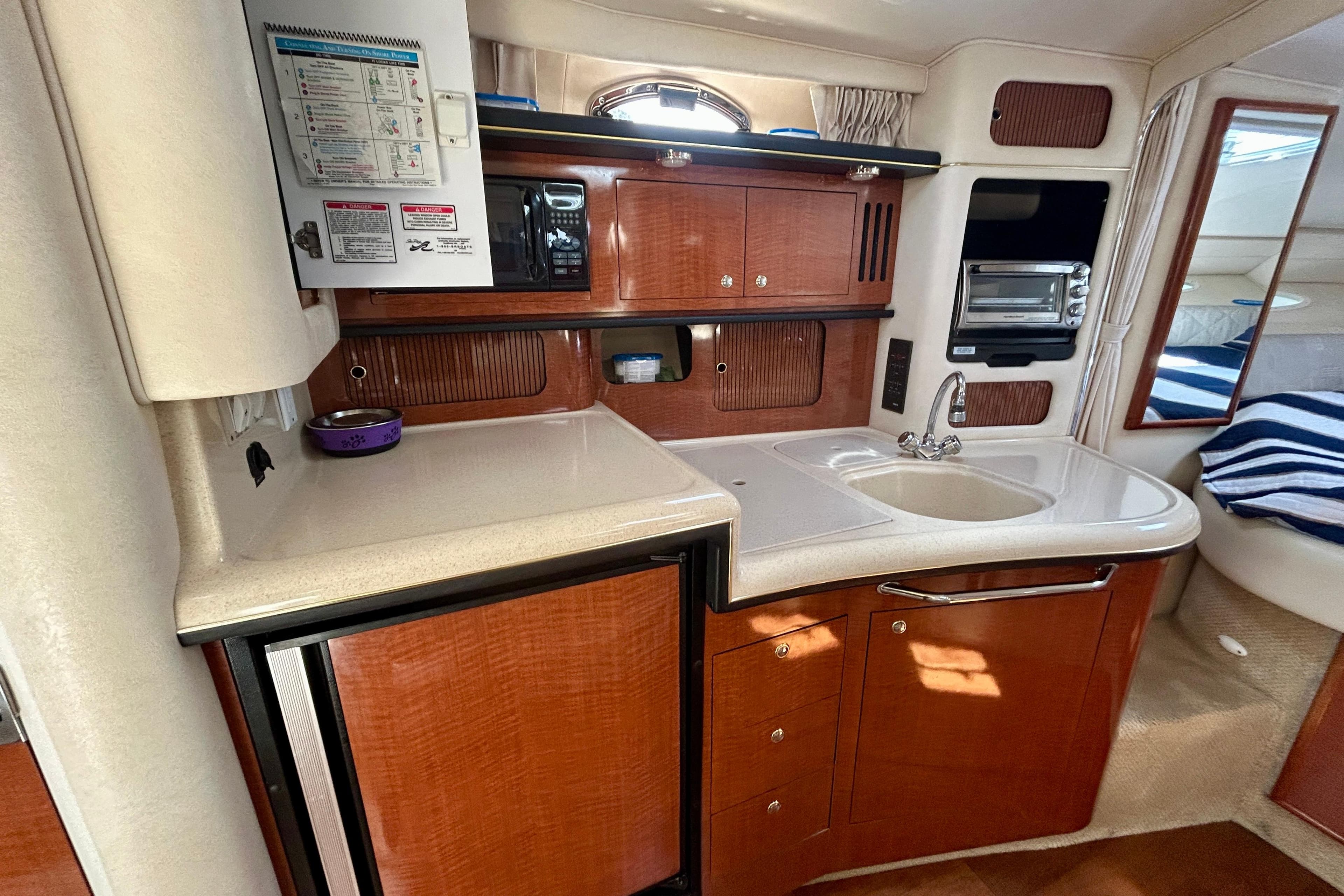 2002 Sea Ray 340 Sundancer galley with wood cabinetry, sink, and appliances.