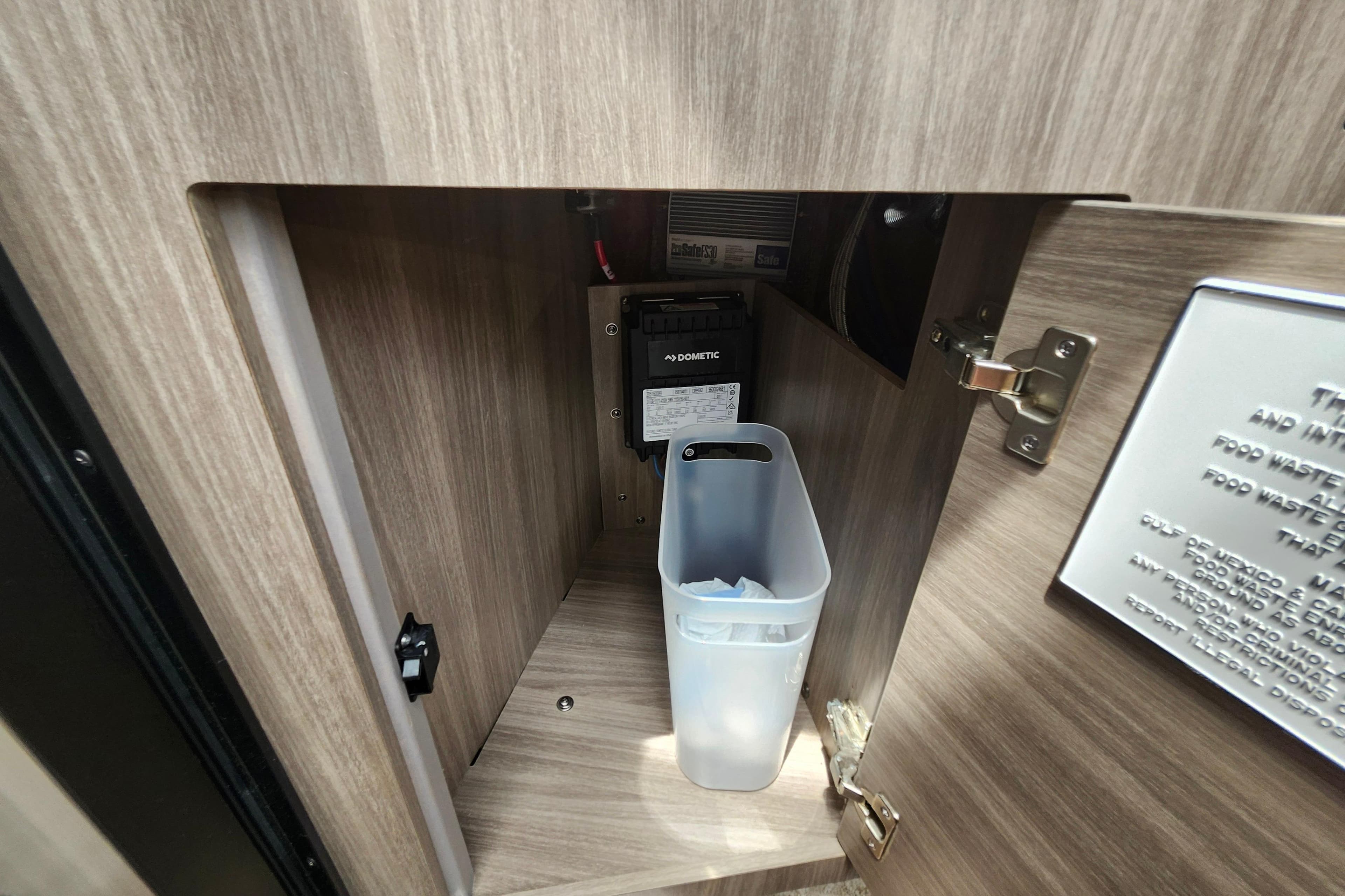 Interior cabinet of 2022 Regal 26 XO boat with waste bin and Dometic control panel.