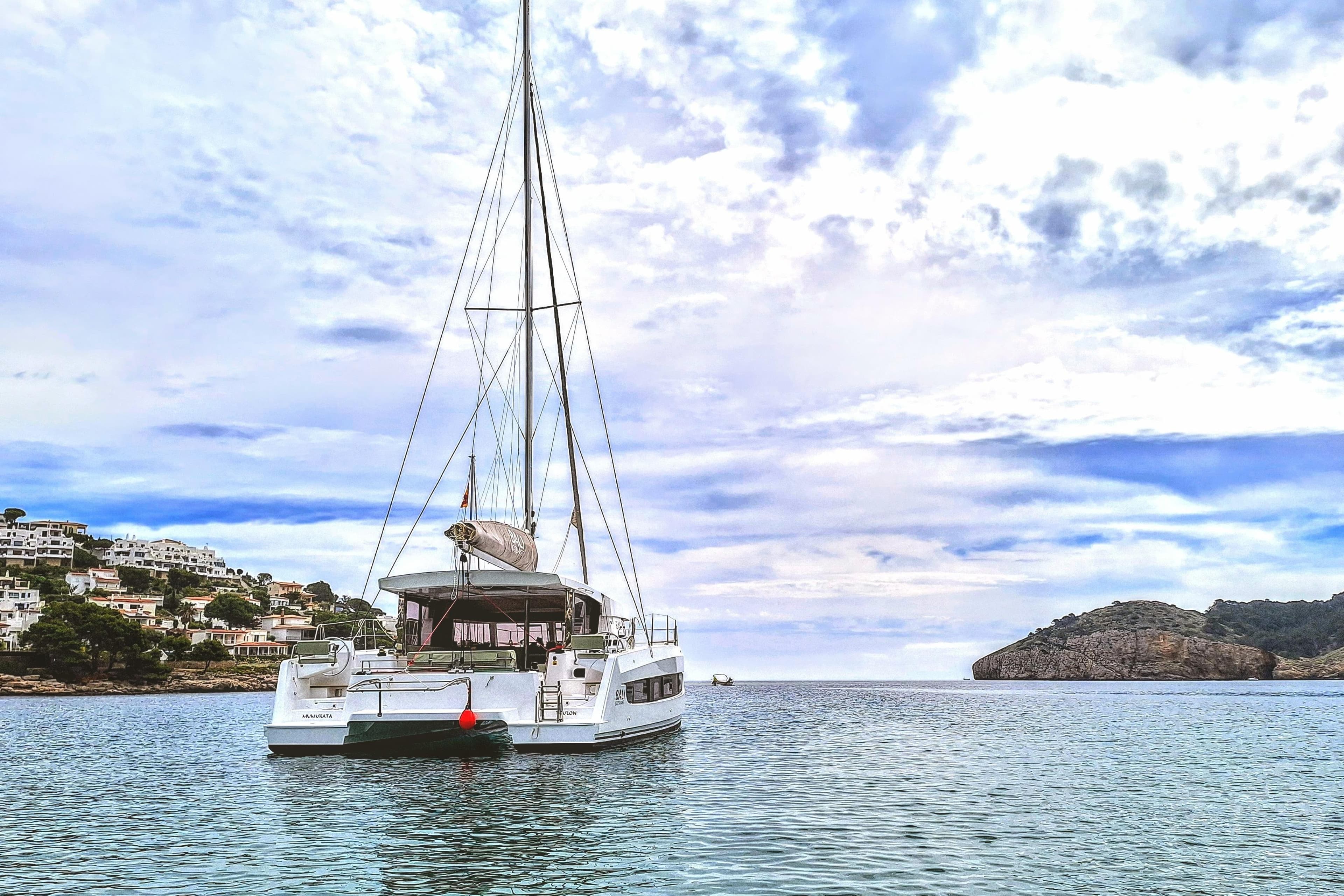 2024 Bali CATSMART catamaran anchored in scenic coastal waters under a partly cloudy sky.