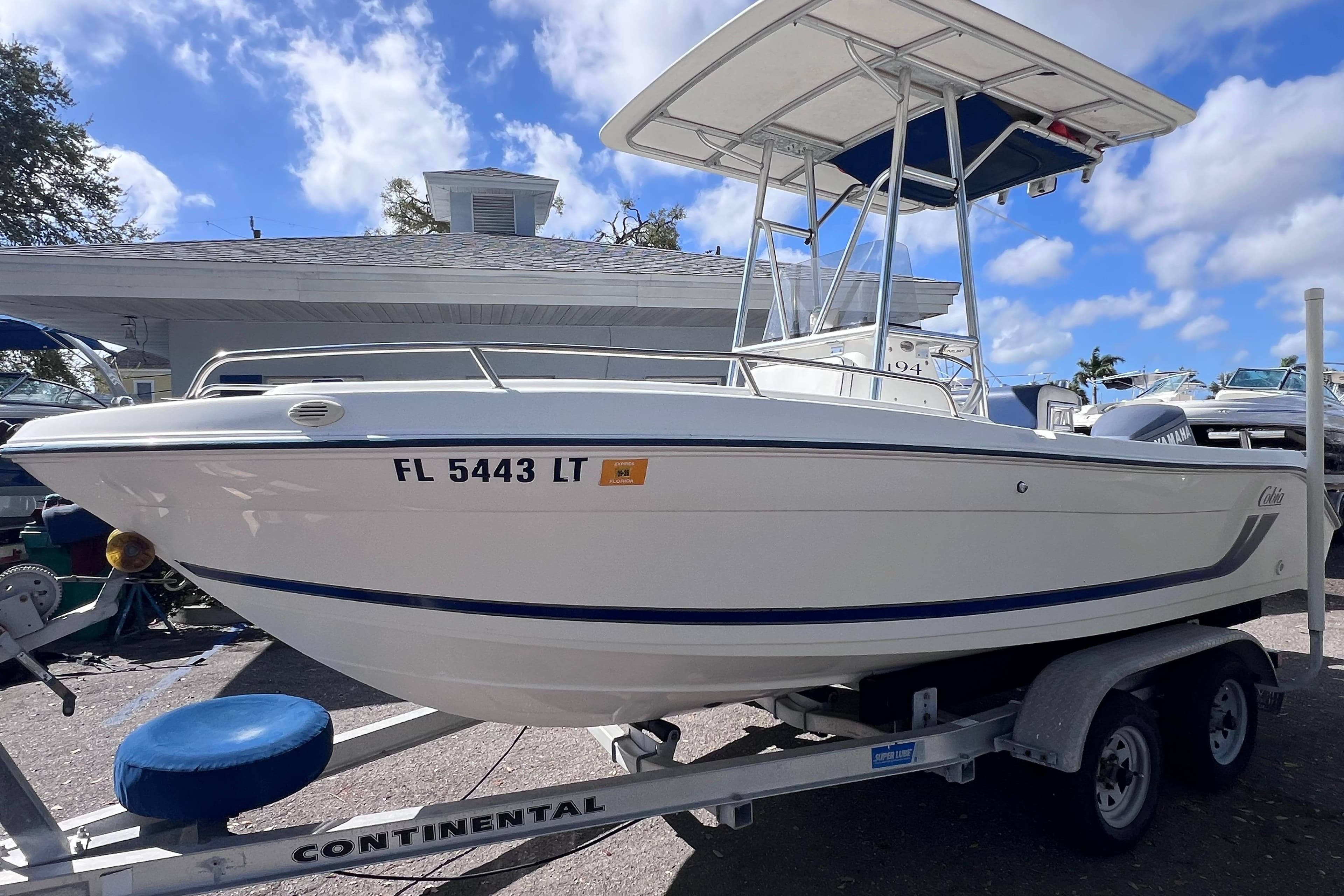 2001 Cobia 194 Center Console boat on trailer under blue sky.