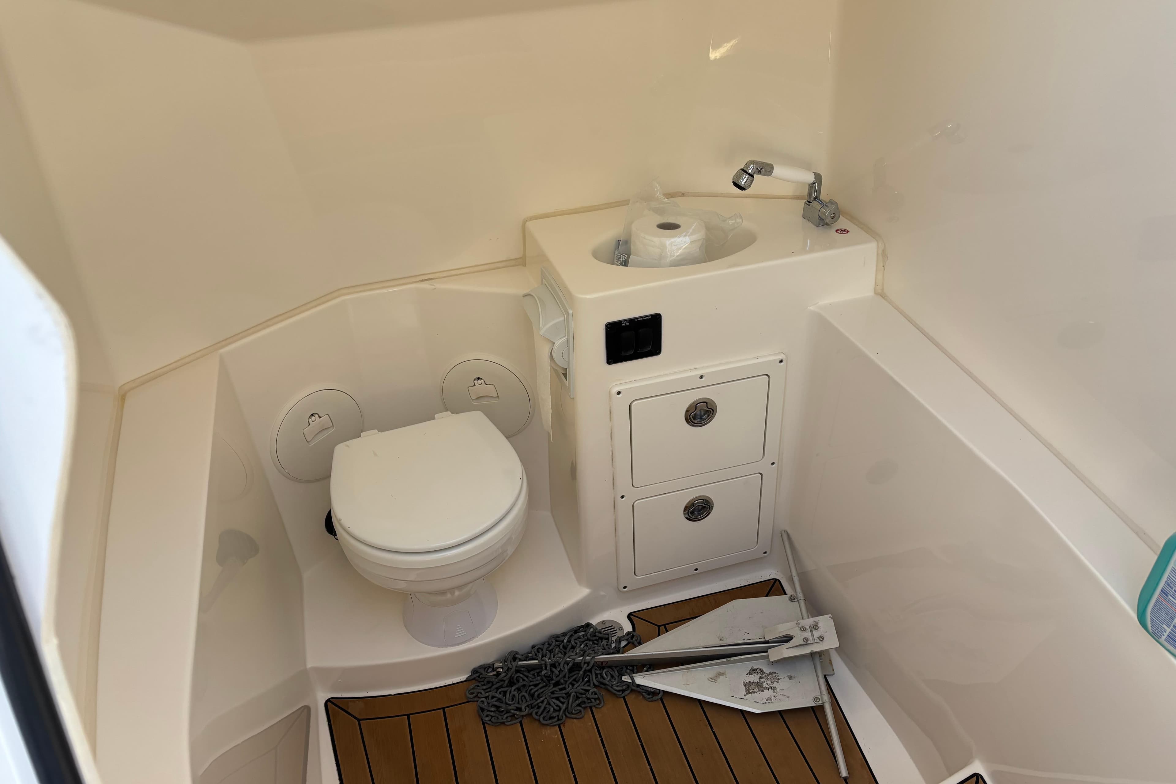 2023 Cobia 301 Center Console boat bathroom with toilet, sink, and storage.
