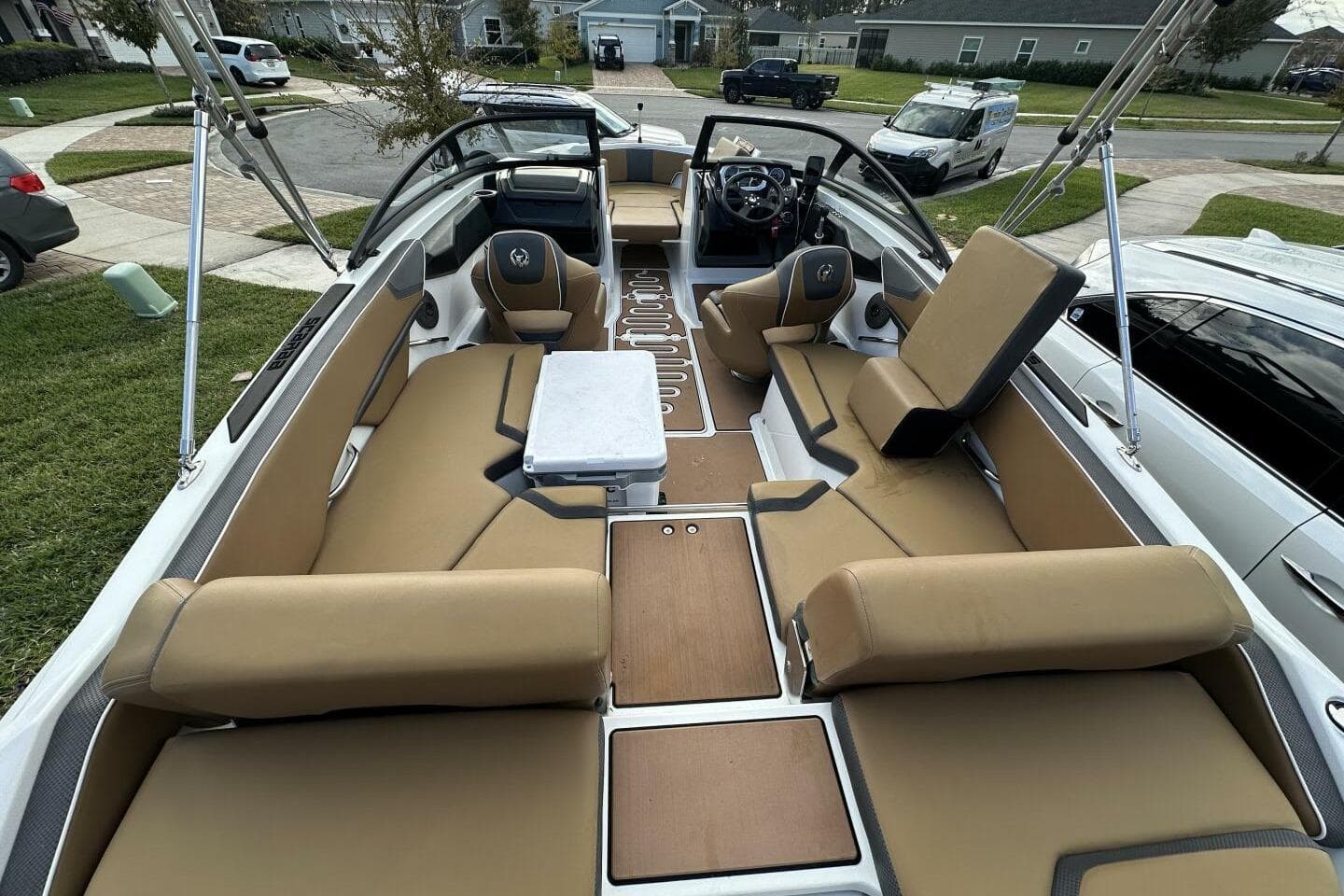 2021 Scarab 215 boat interior with tan seating and modern dashboard in a residential area.