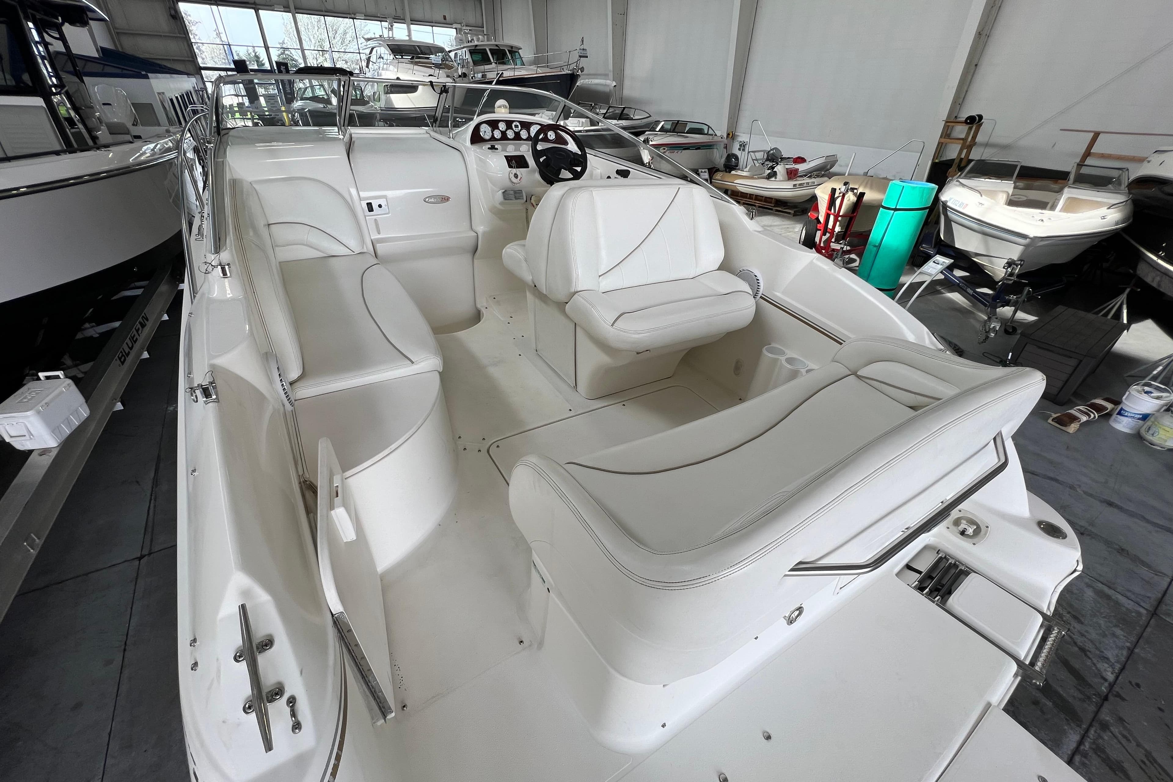 2002 Larson Cabrio 254 boat interior with white seating in a showroom.