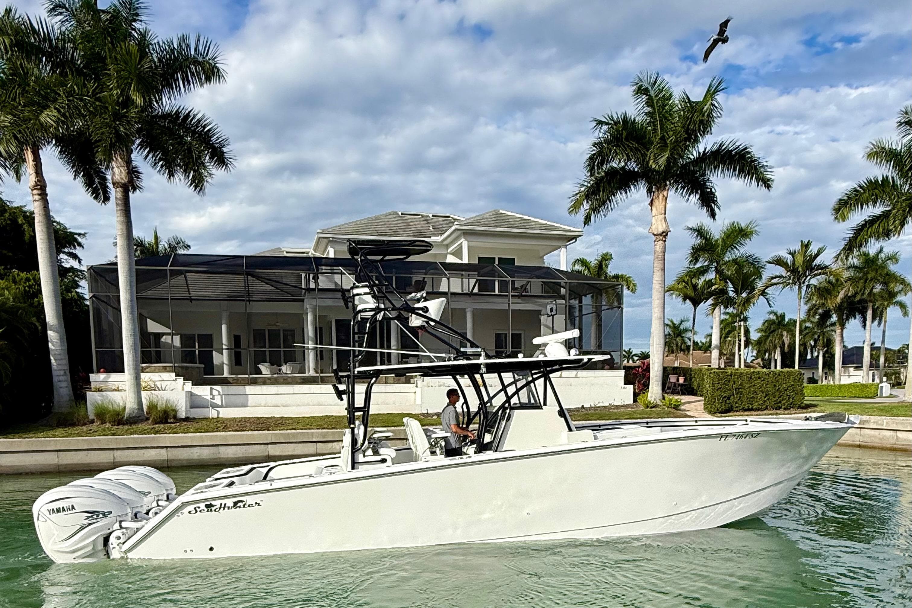 2020 SeaHunter 41 CTS boat cruising near a waterfront home with palm trees.