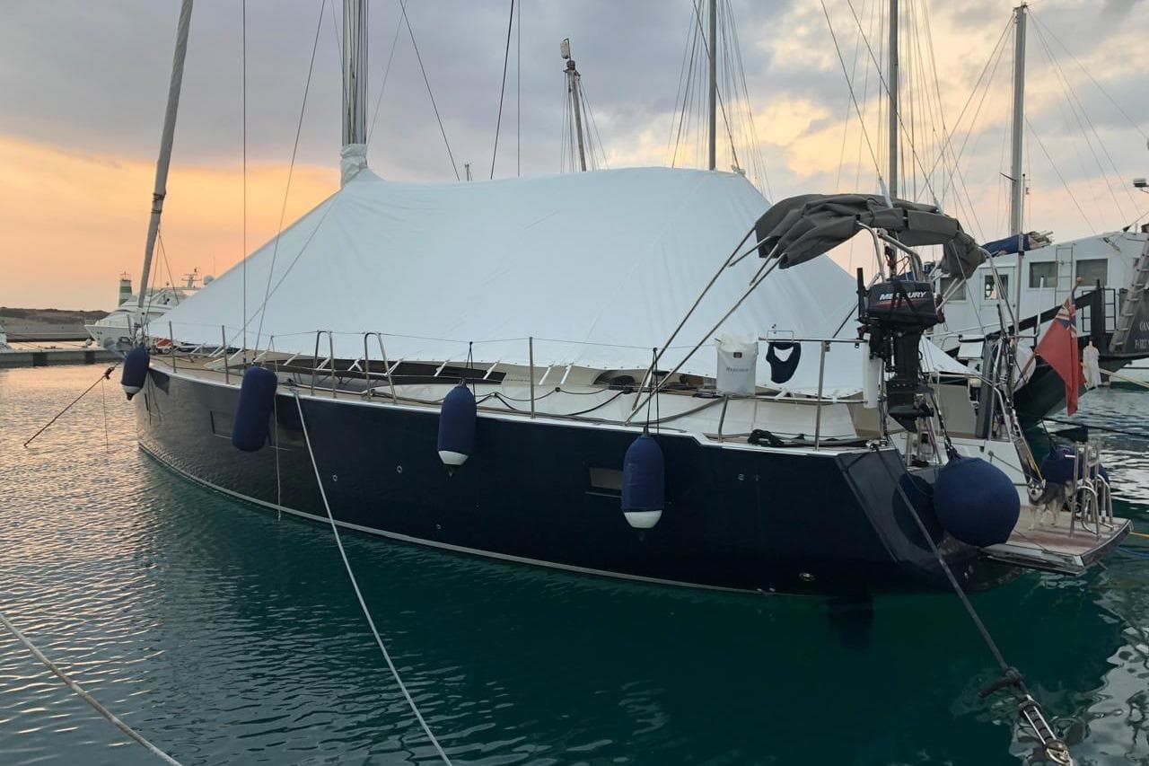 2018 Jeanneau 54 yacht docked at marina, covered, with sunset in background.