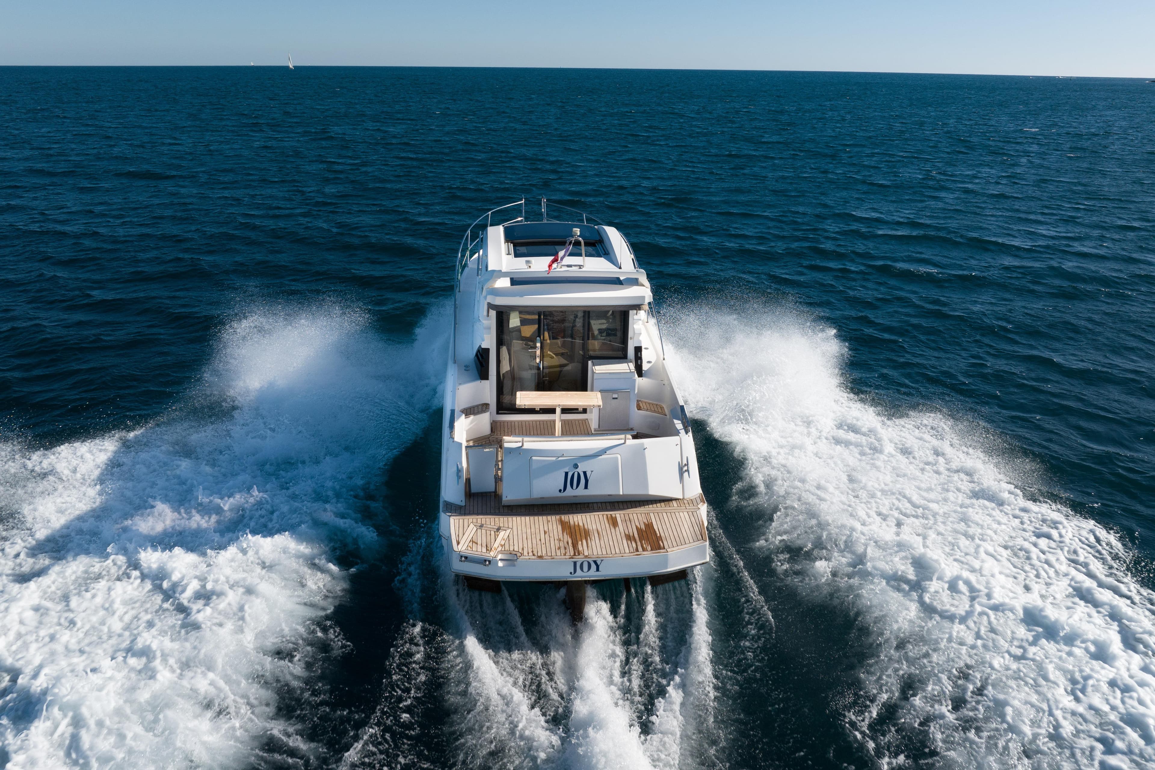 2017 Galeon 310 HTC yacht cruising on open sea, rear view.