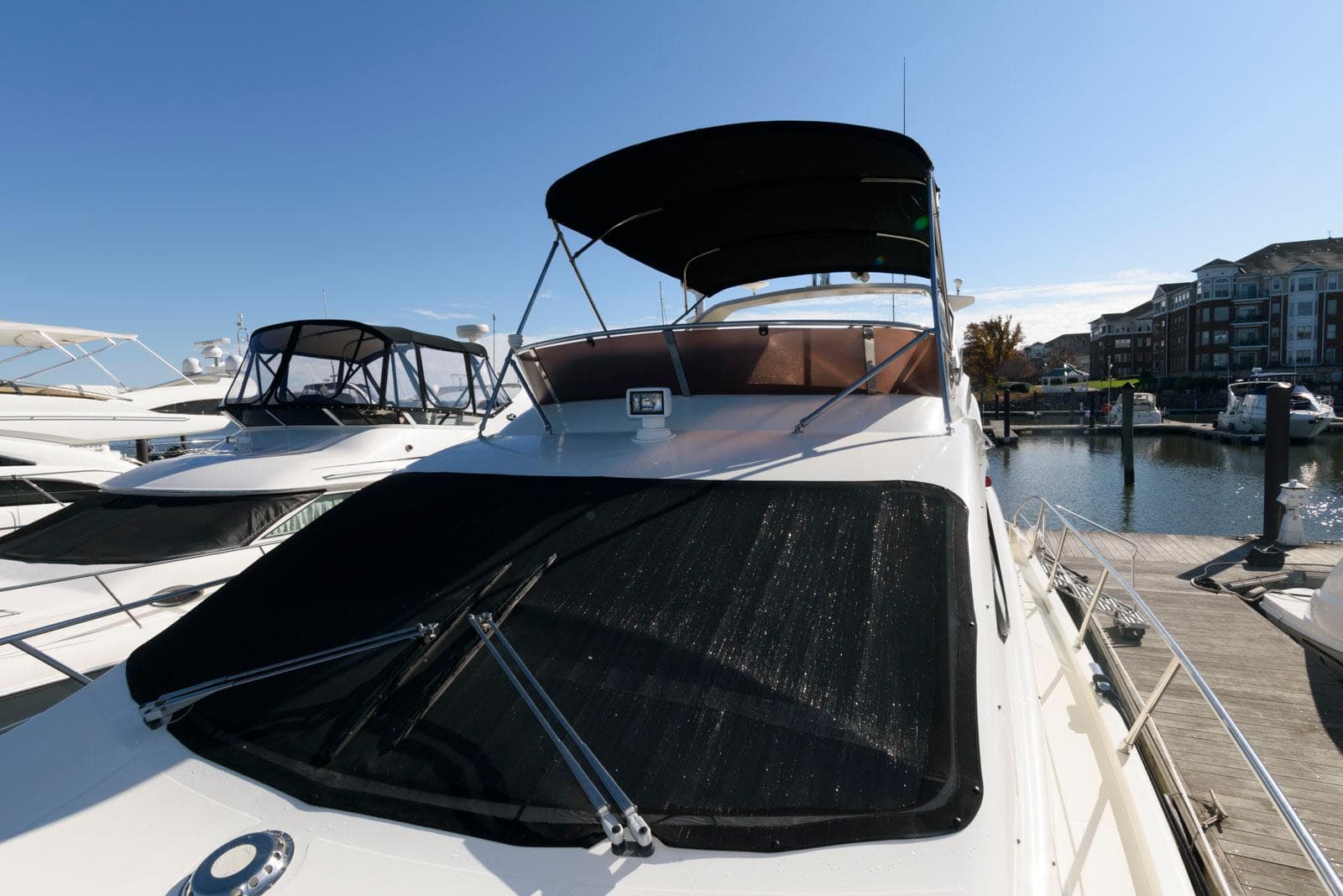 2005 Azimut 50 Flybridge yacht docked at marina under clear blue sky.