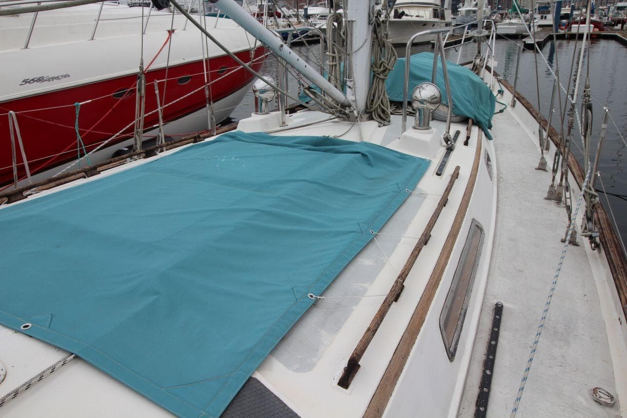 1985 Passport 47 sailboat deck with teal cover, docked in marina.