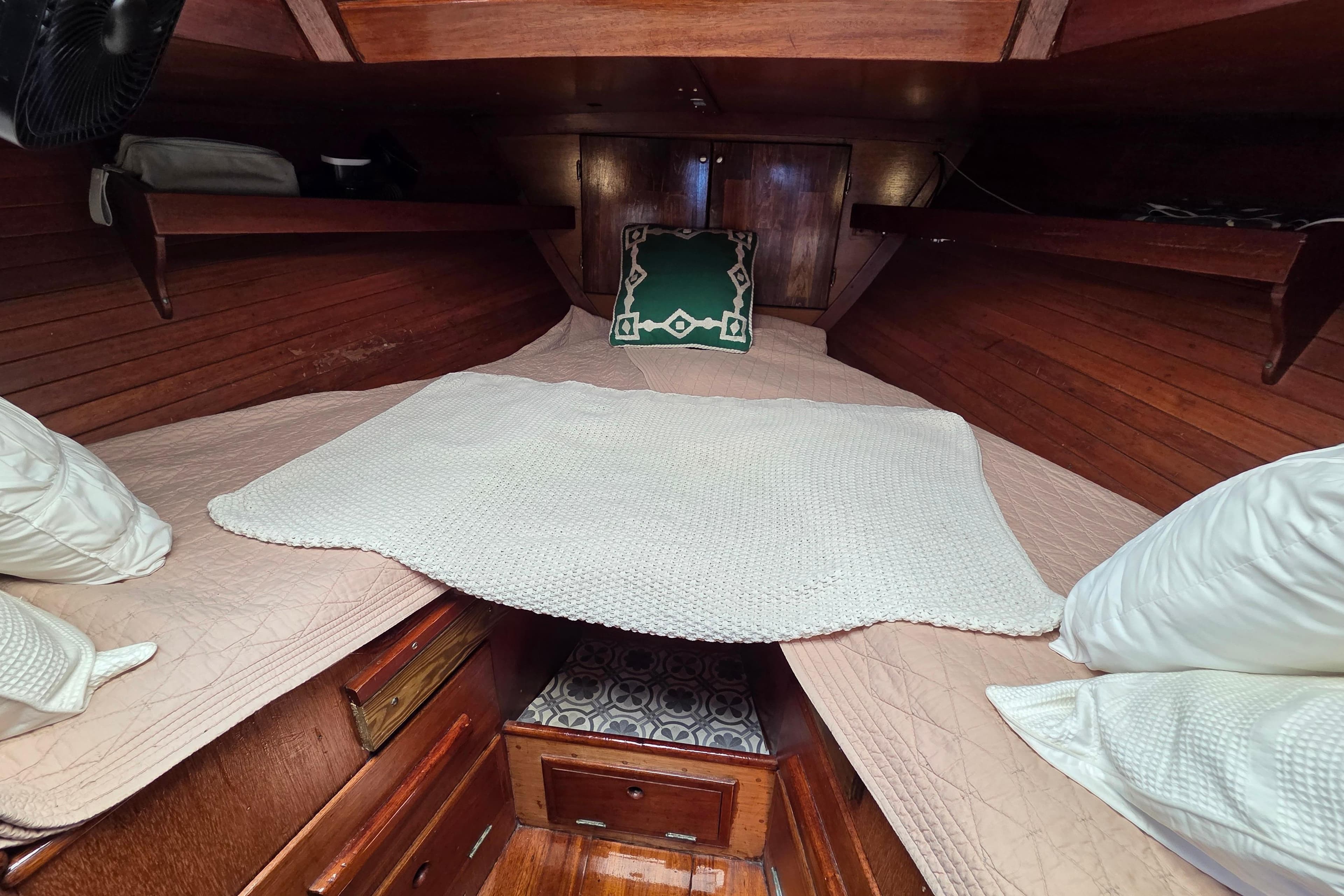 Cozy cabin interior of 1961 Hinckley Bermuda 40 sailboat with wooden finish and bedding.