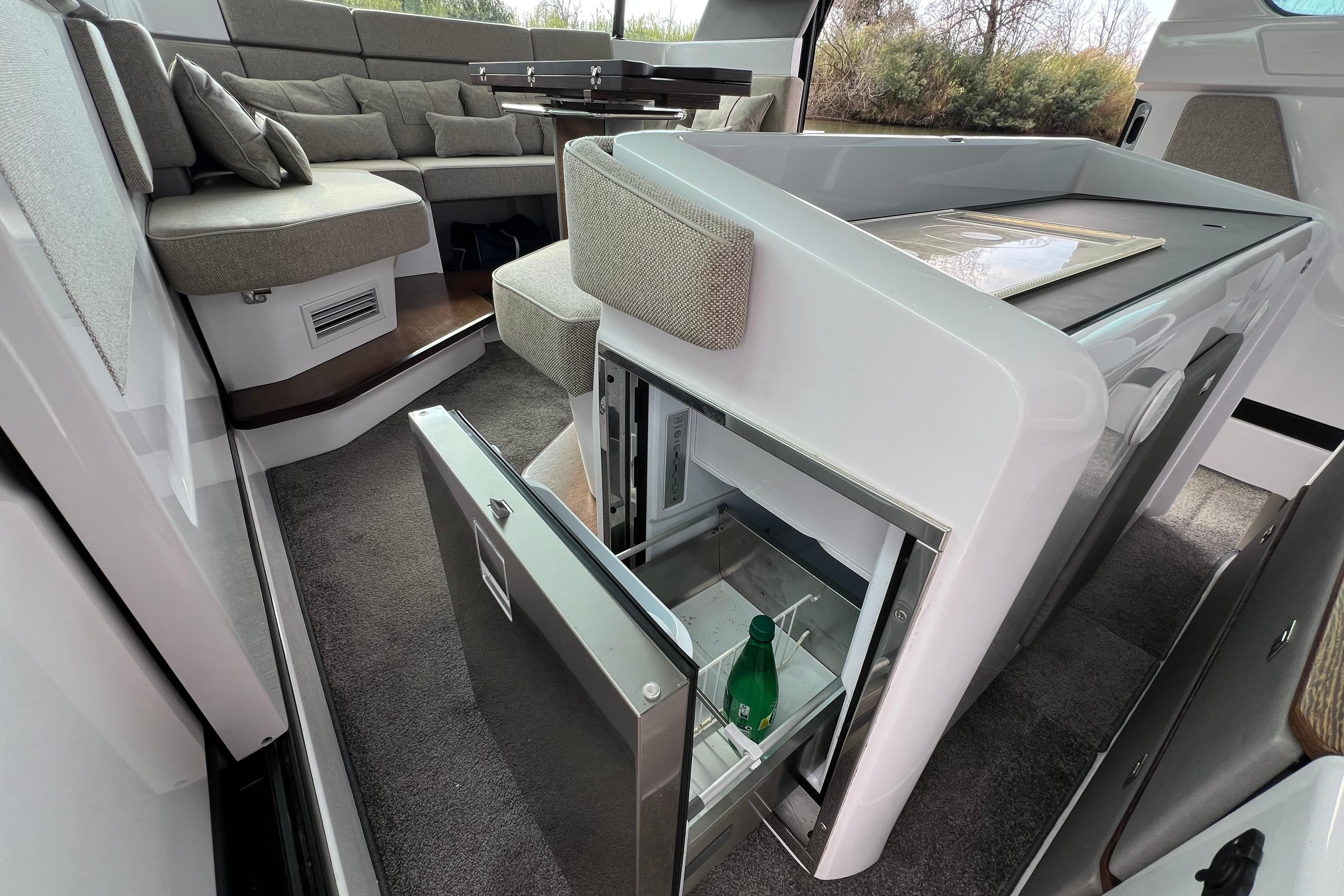 Luxurious interior of 2023 Axopar 45 Cross Cabin with open fridge and seating area.