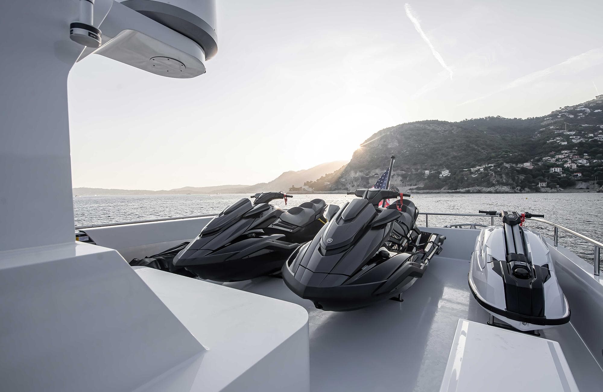 Luxury Outer Reef Yachts 27 Crossover with jet skis, 2027 model, at sunset on the water.