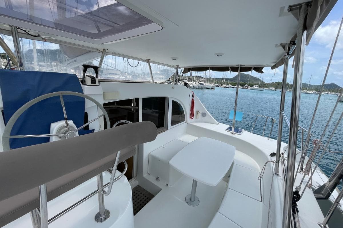 2014 Lagoon 380 S2 catamaran cockpit with steering wheel and seating, docked in marina.