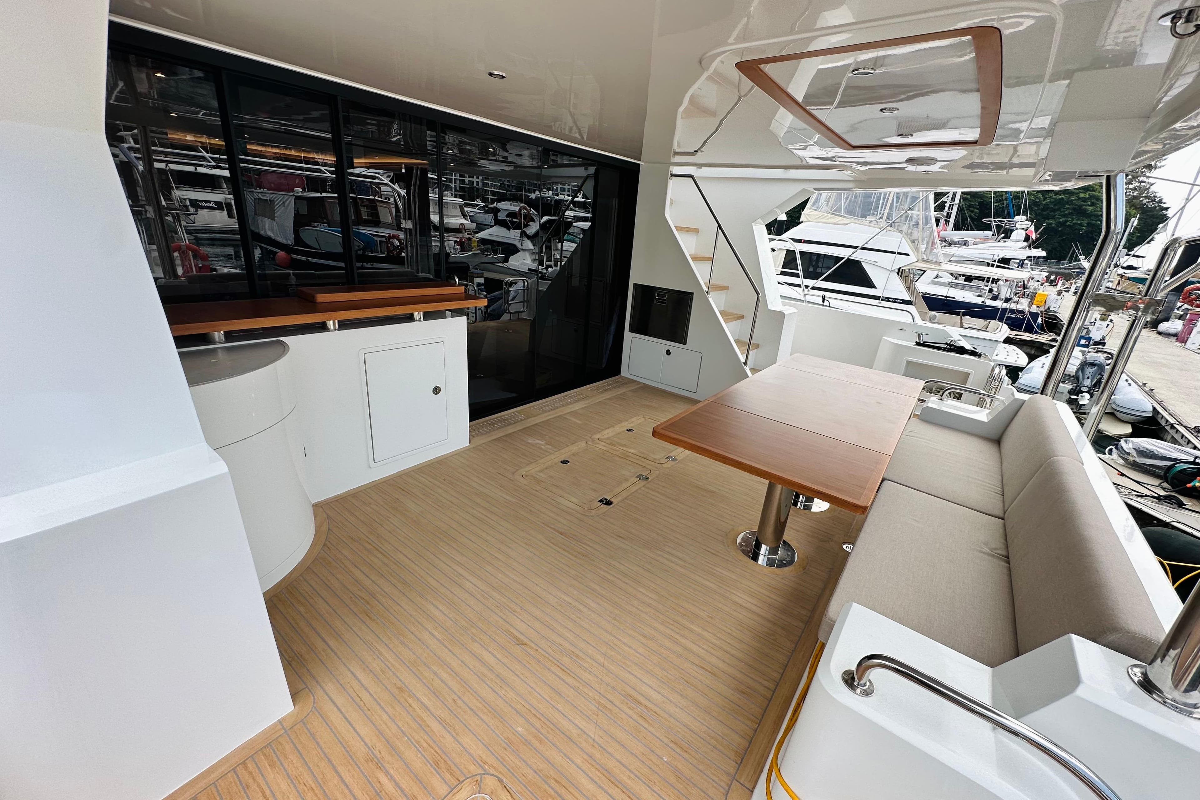 Luxurious 2022 ILIAD 50 yacht deck with seating, table, and marina view.