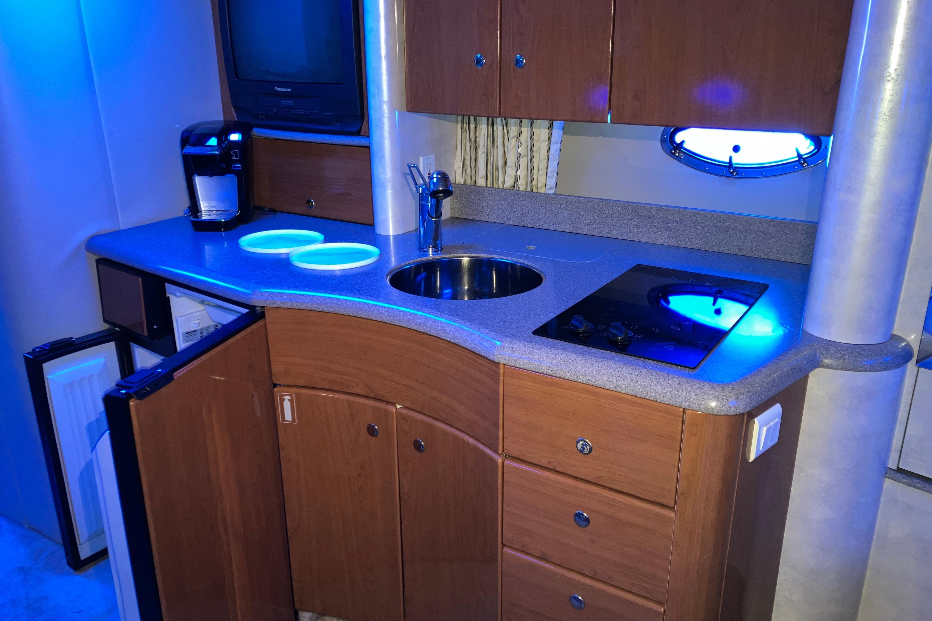 2001 Formula 37 Performance Cruiser kitchen with sink, stove, and cabinets under blue lighting.