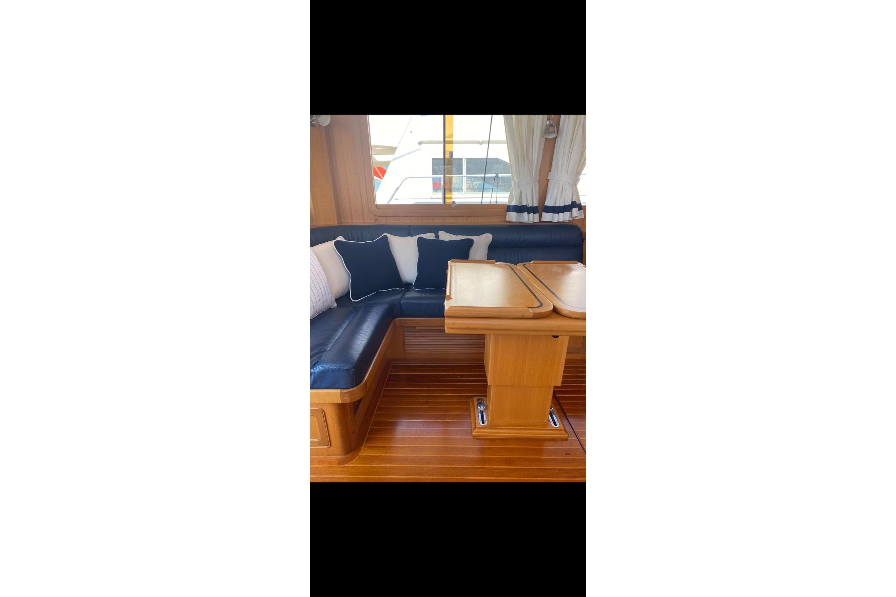 Interior of 2005 Selene 47 yacht with wooden table and cushioned seating.