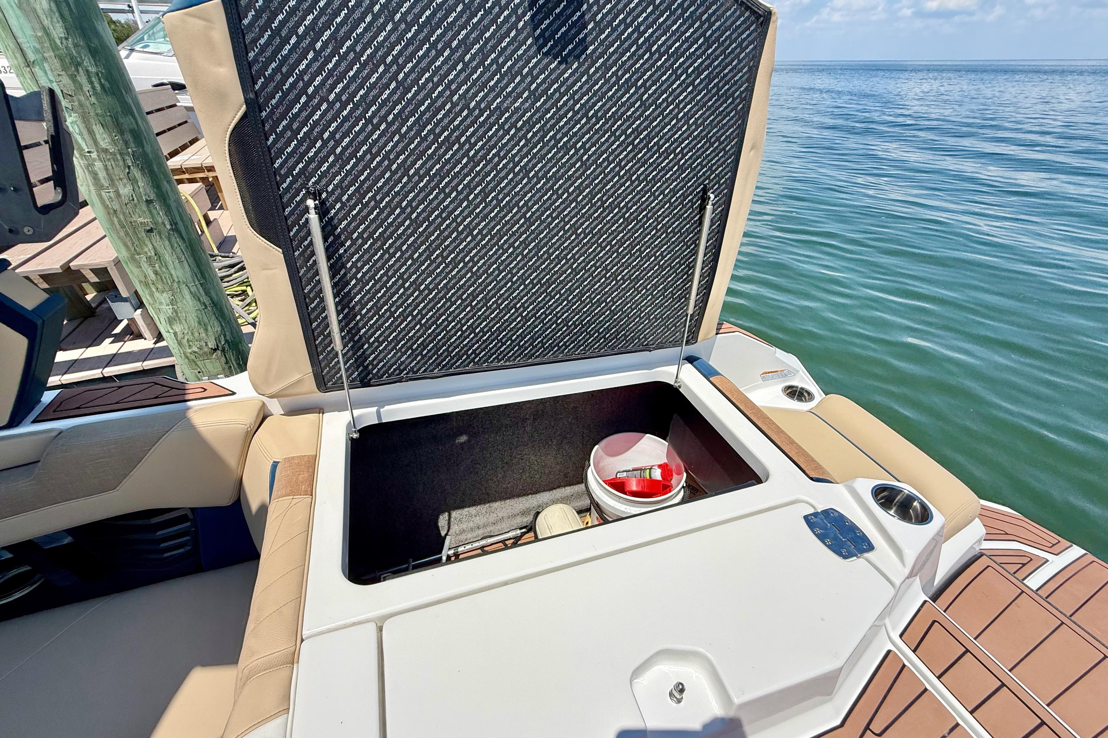 2021 Nautique Super Air Nautique G21 boat storage compartment open by the water.