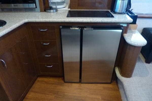 2009 Carver 41 Cockpit Motor Yacht kitchen with stainless steel fridge and wooden cabinetry.